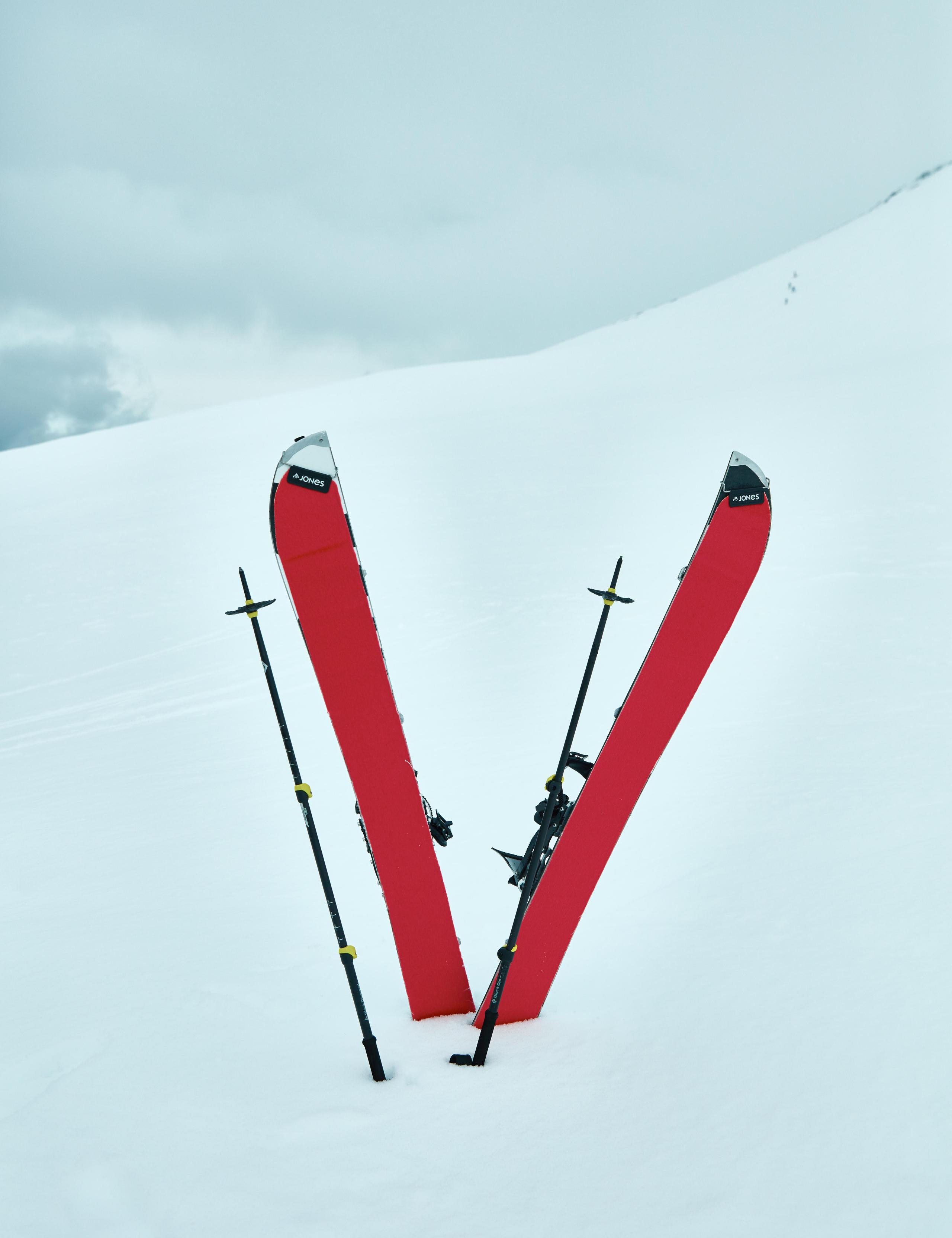 Two red skis sticking out of snowy landscape in the shape of a V
