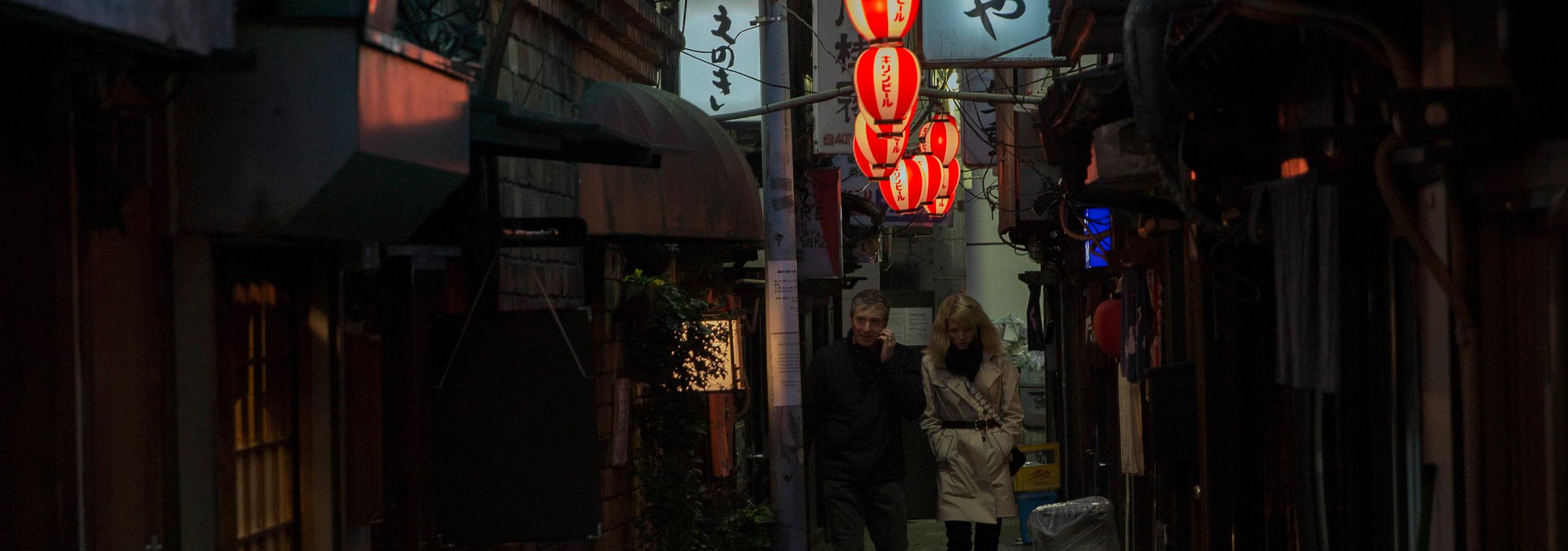 Couple walking through alleyways of Tokyo at night