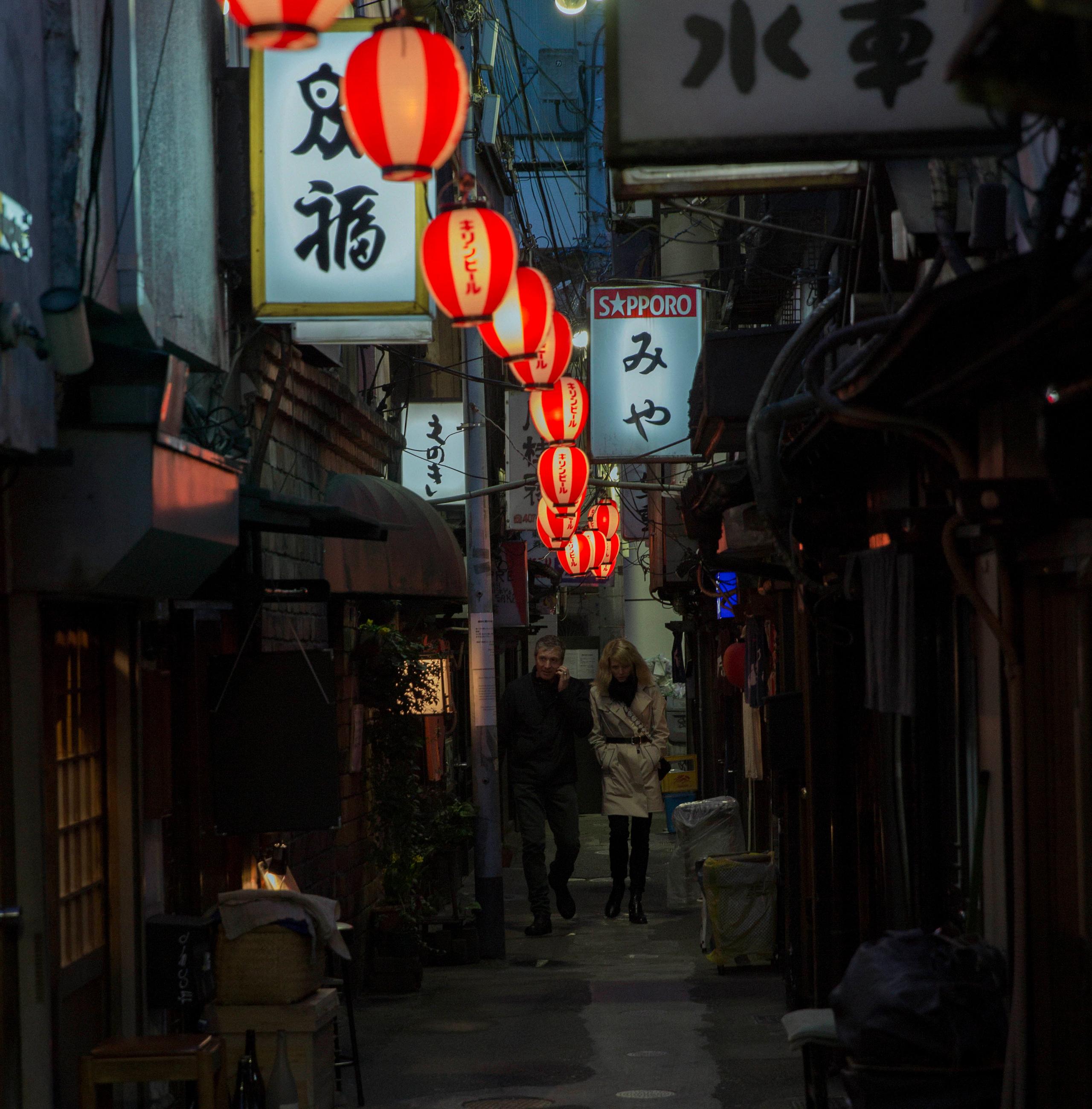 Couple walking through alleyways of Tokyo at night