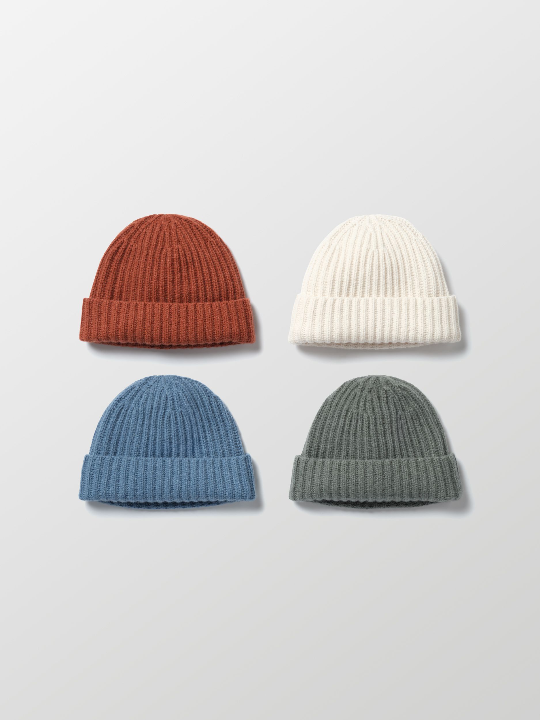 Flat lay of Cashmere hats in four colors: Redwood Rust, Winter White, Portal Blue, and Gunmetal