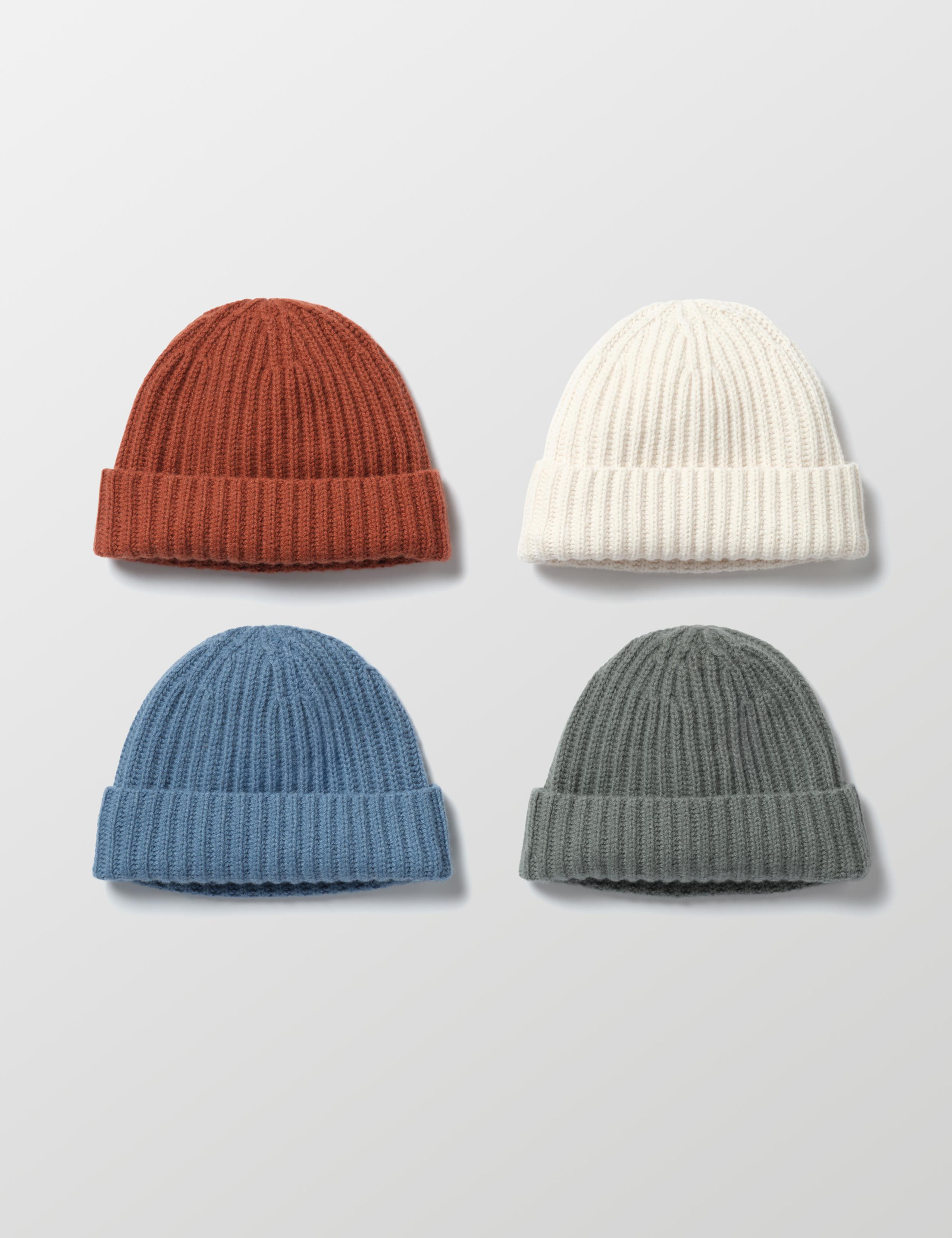 Flat lay of Cashmere hats in four colors: Redwood Rust, Winter White, Portal Blue, and Gunmetal