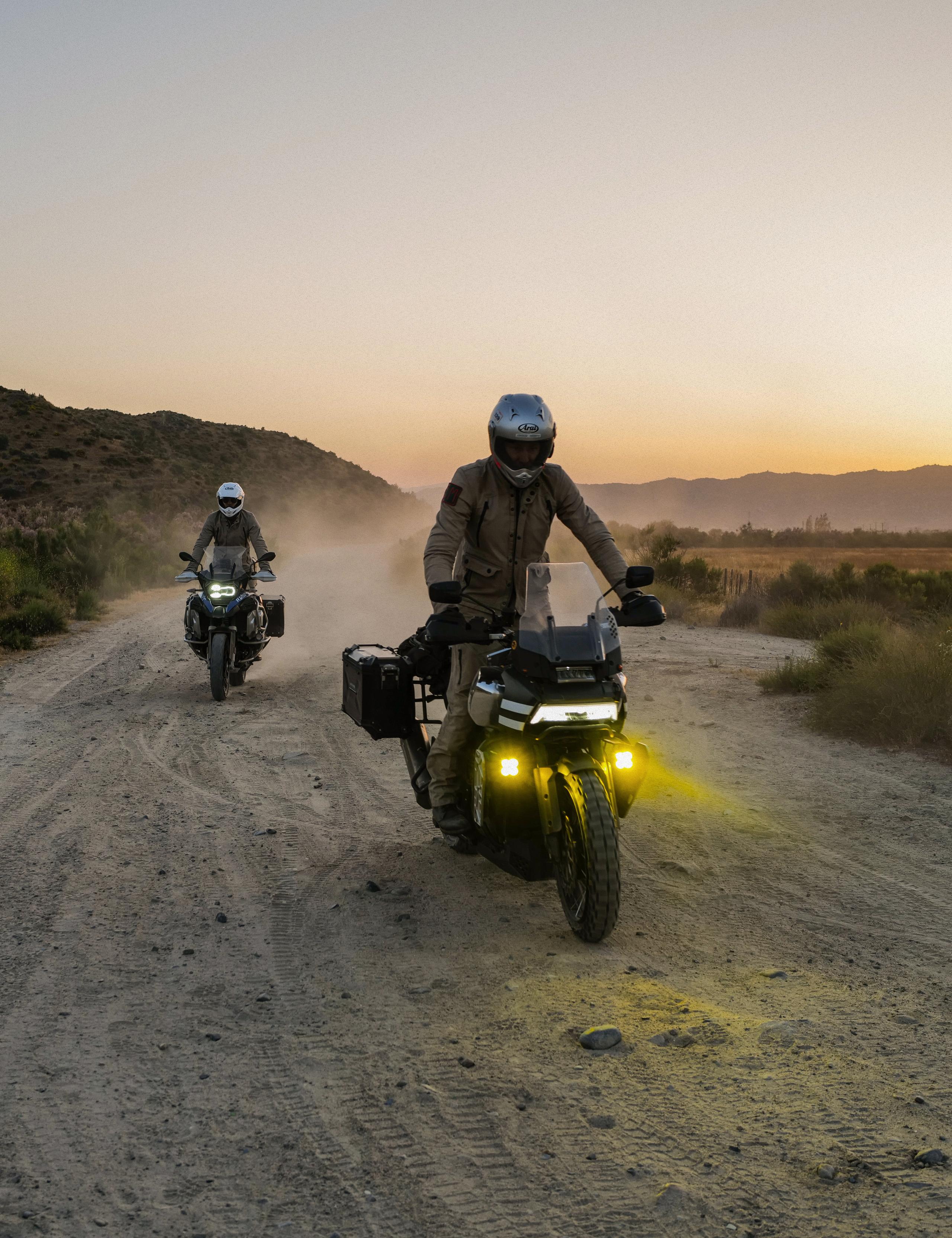 Two motorcyclists riding on dirt path in Baja California at dusk