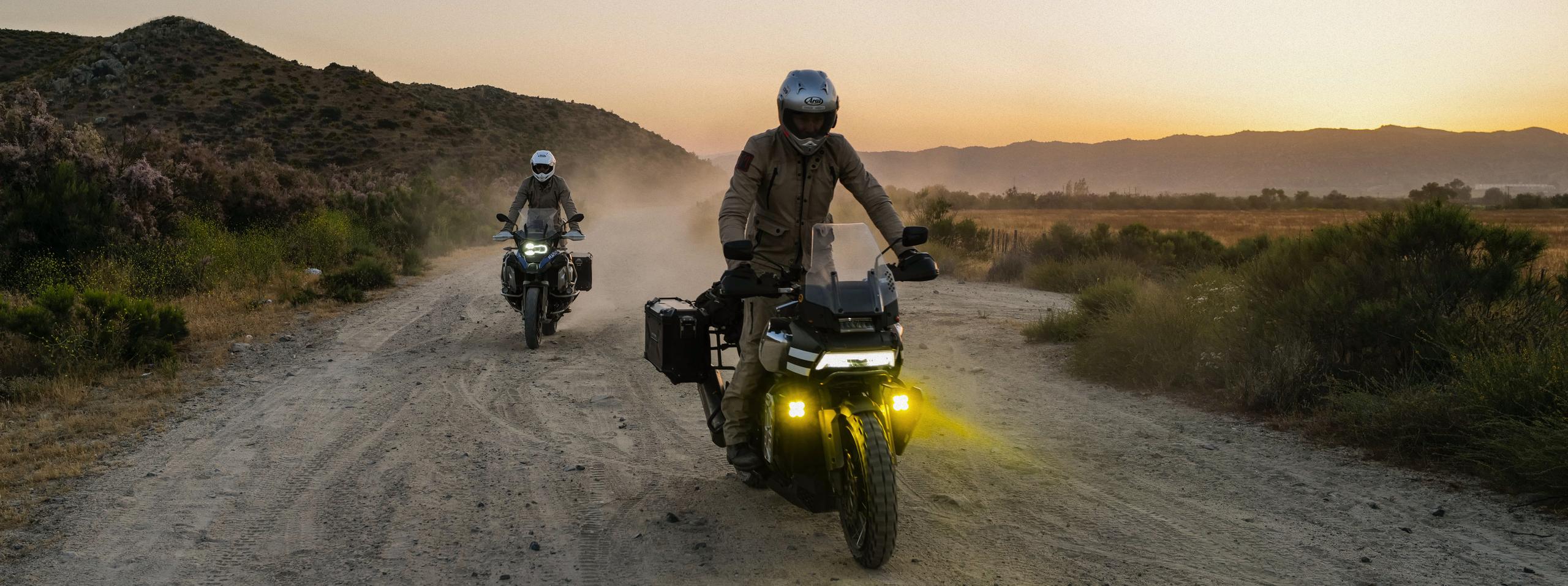 Two motorcyclists riding down dirt path in Baja California at sunset