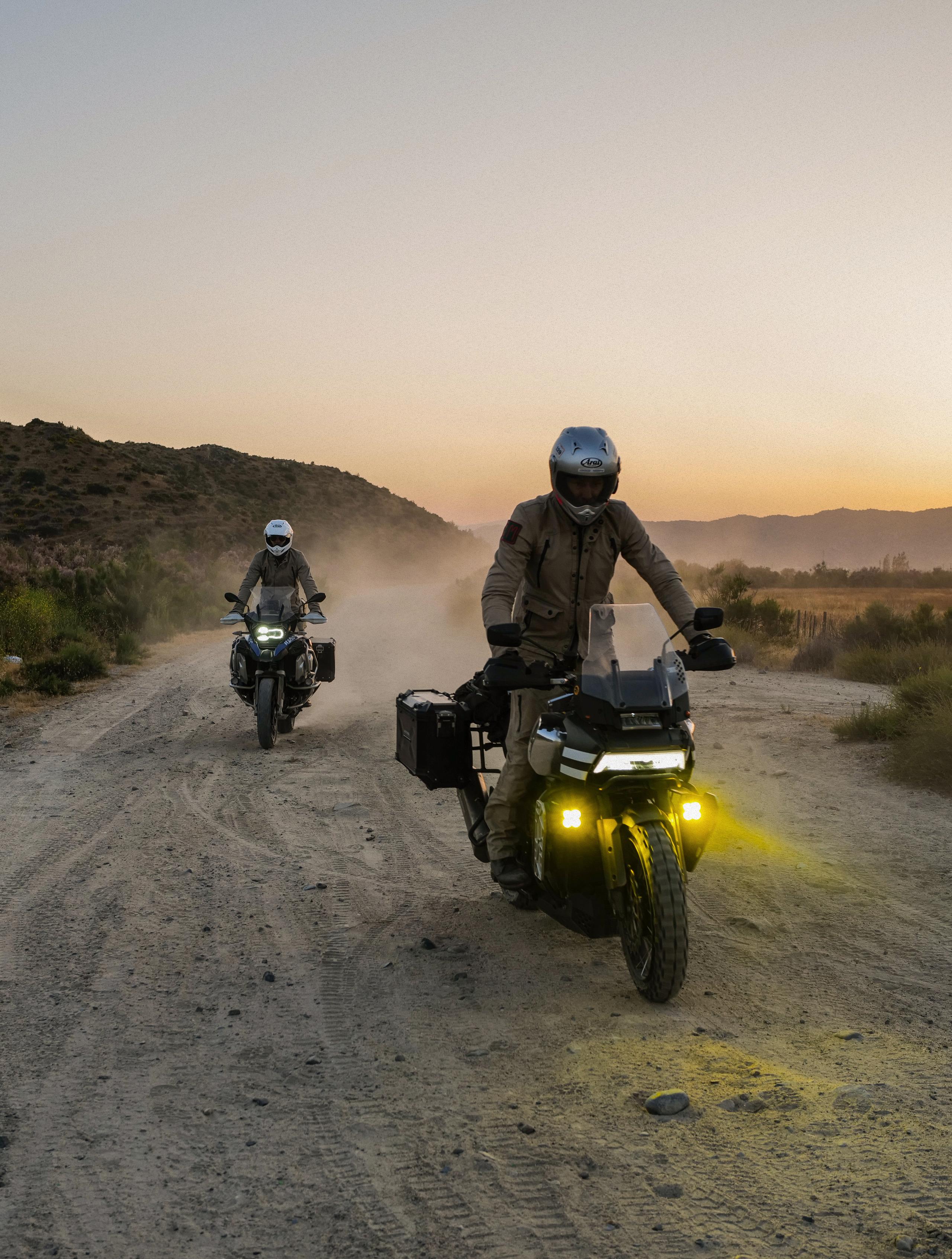Two motorcyclists at dusk riding down dirt path in Baja California