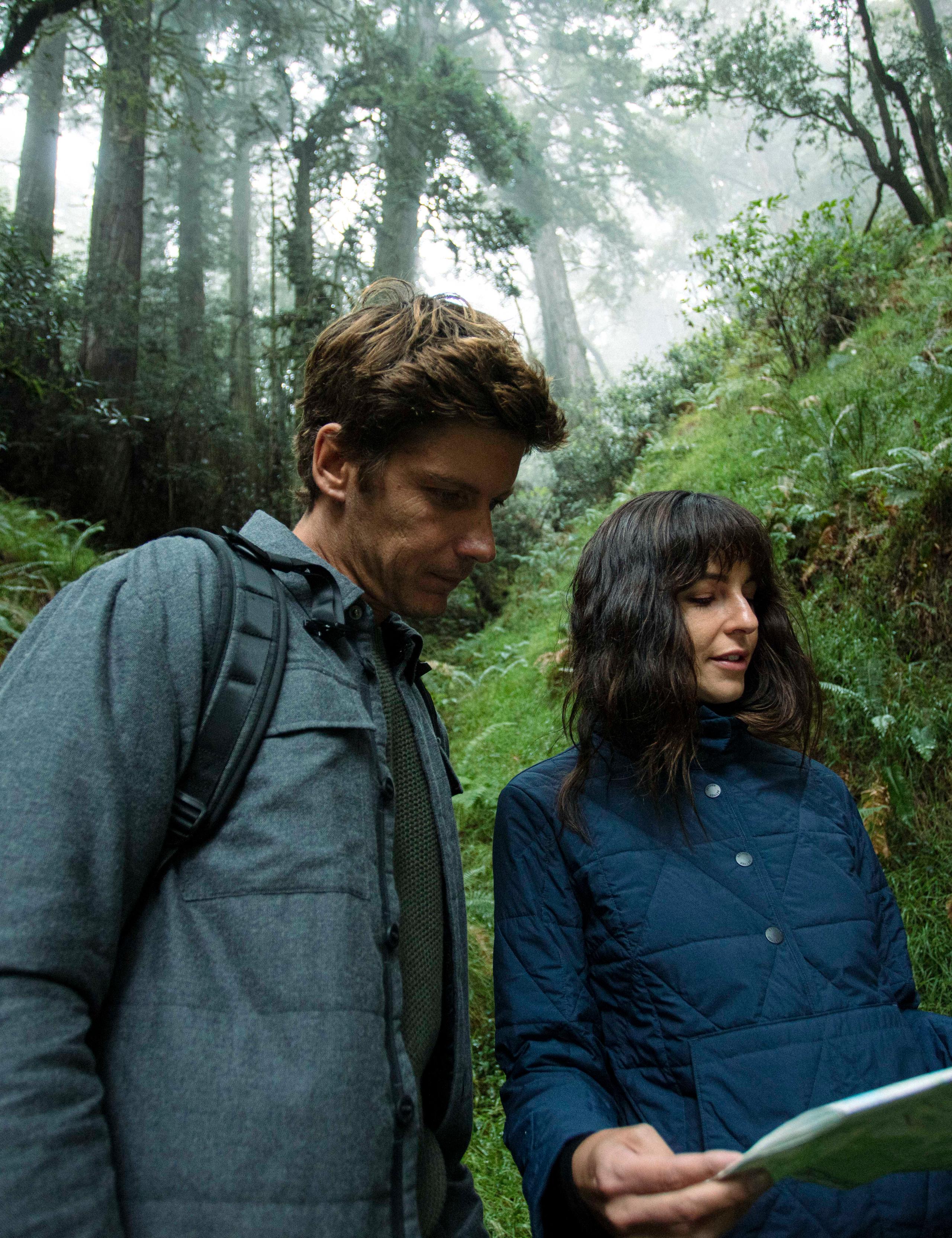 A couple looking at a map in forest