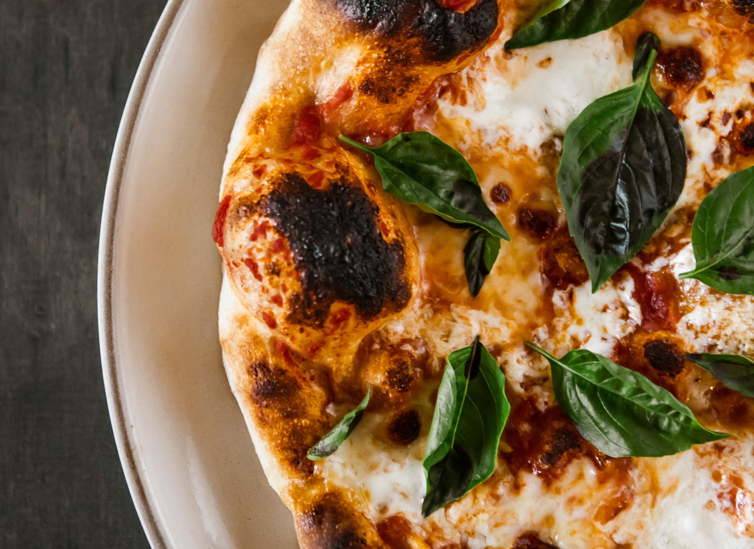 Closeup view of margherita pizza with whole basil leaves on top