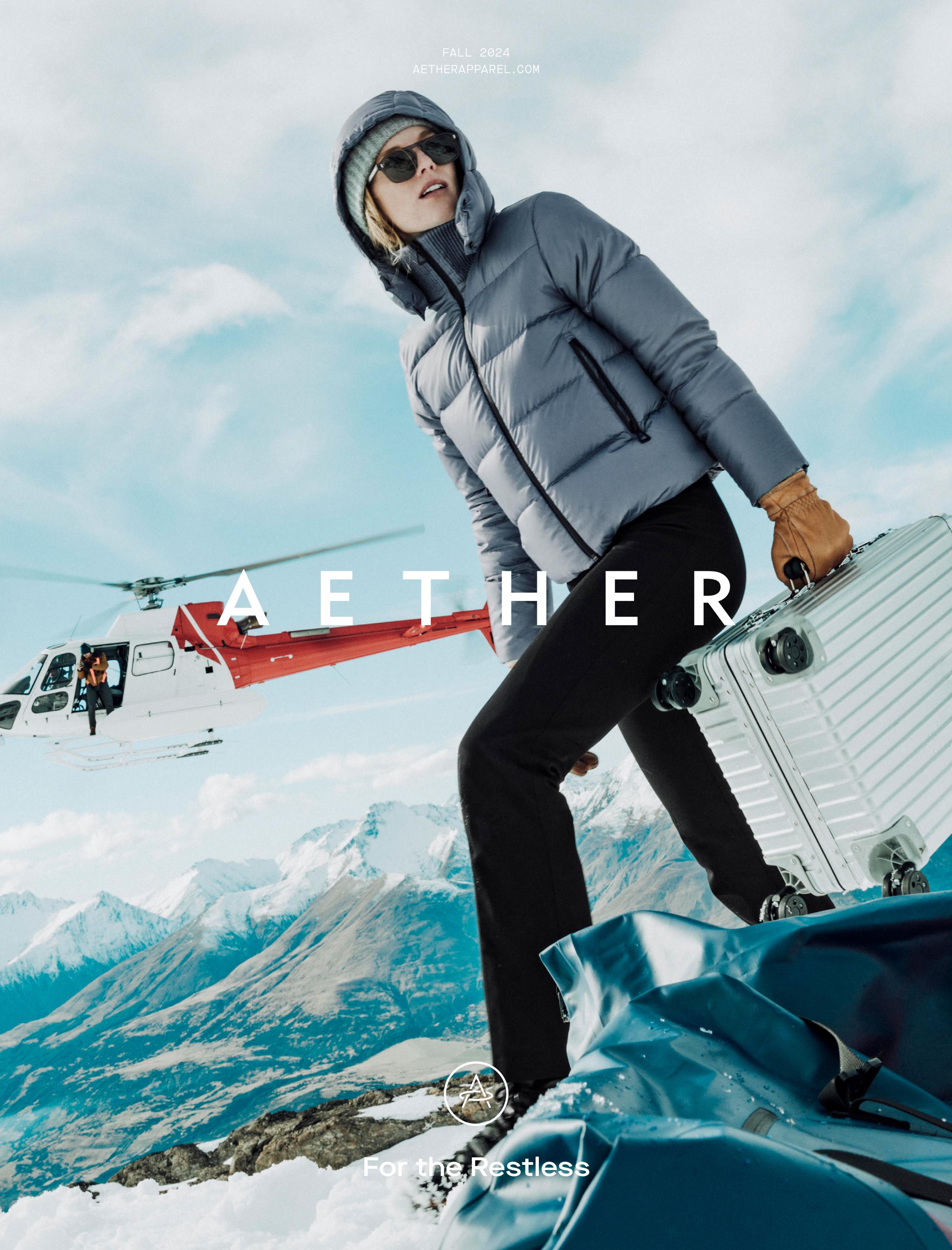 Cover of Fall 2024 AETHER Catalog with woman on snowy mountain carrying luggage with helicopter in the background