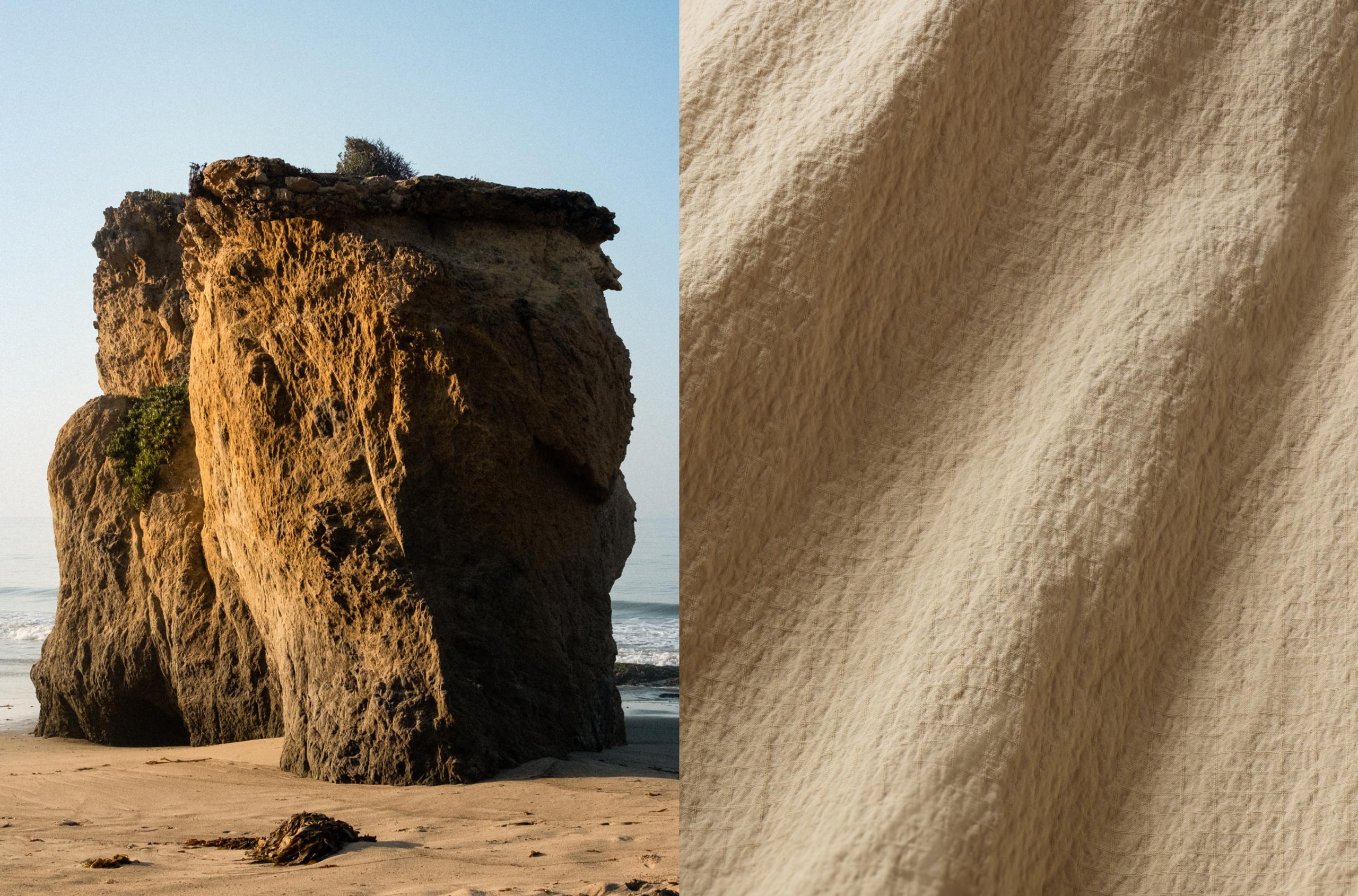 Closeup view of Harrier Anorak desert tan fabric juxtaposed next to old boulder formation on a beach alongside the Pacific Ocean
