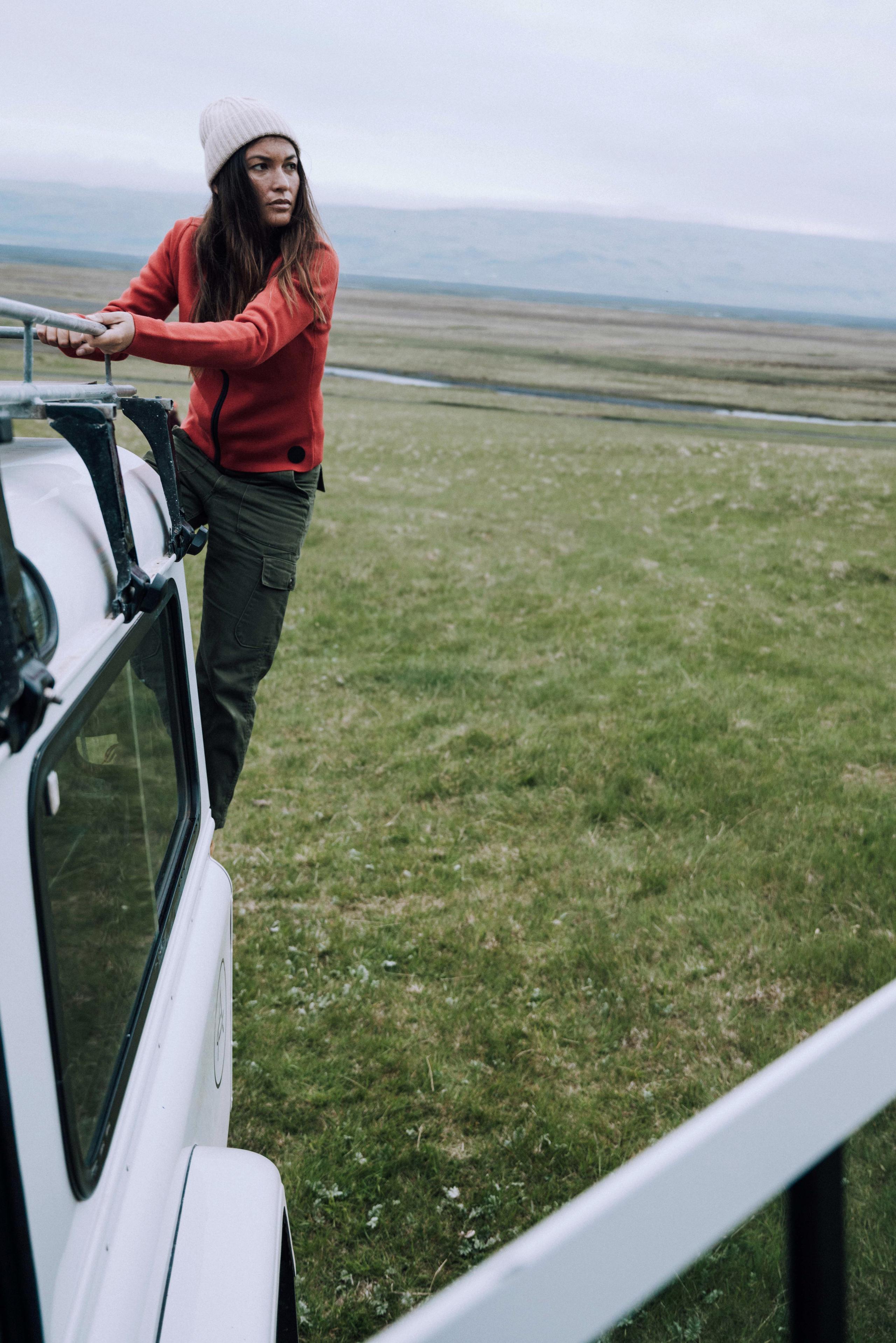 Woman climbing on back of Defender truck in Iceland landscape