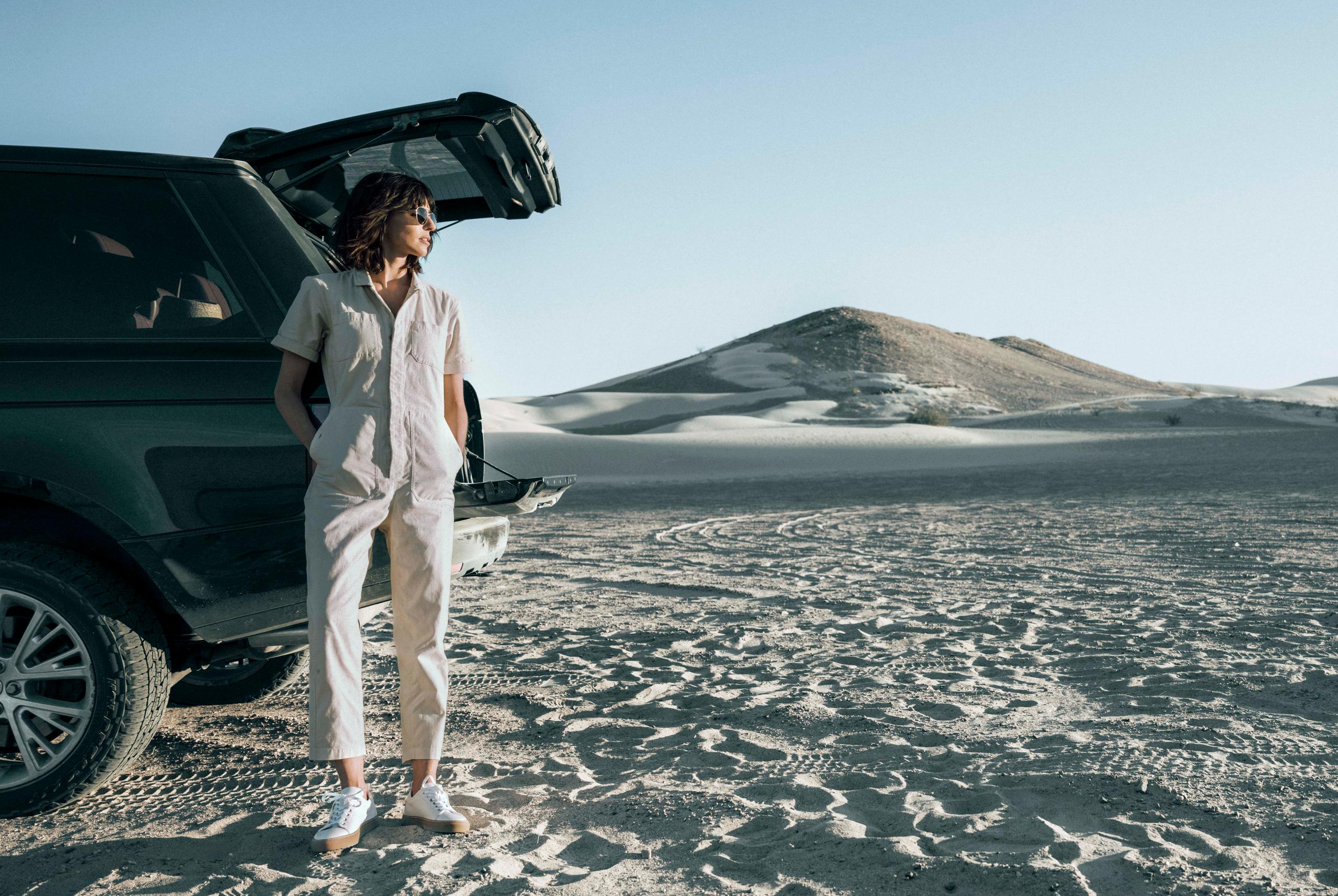 Woman in Bard Jumpsuit leaning against a car