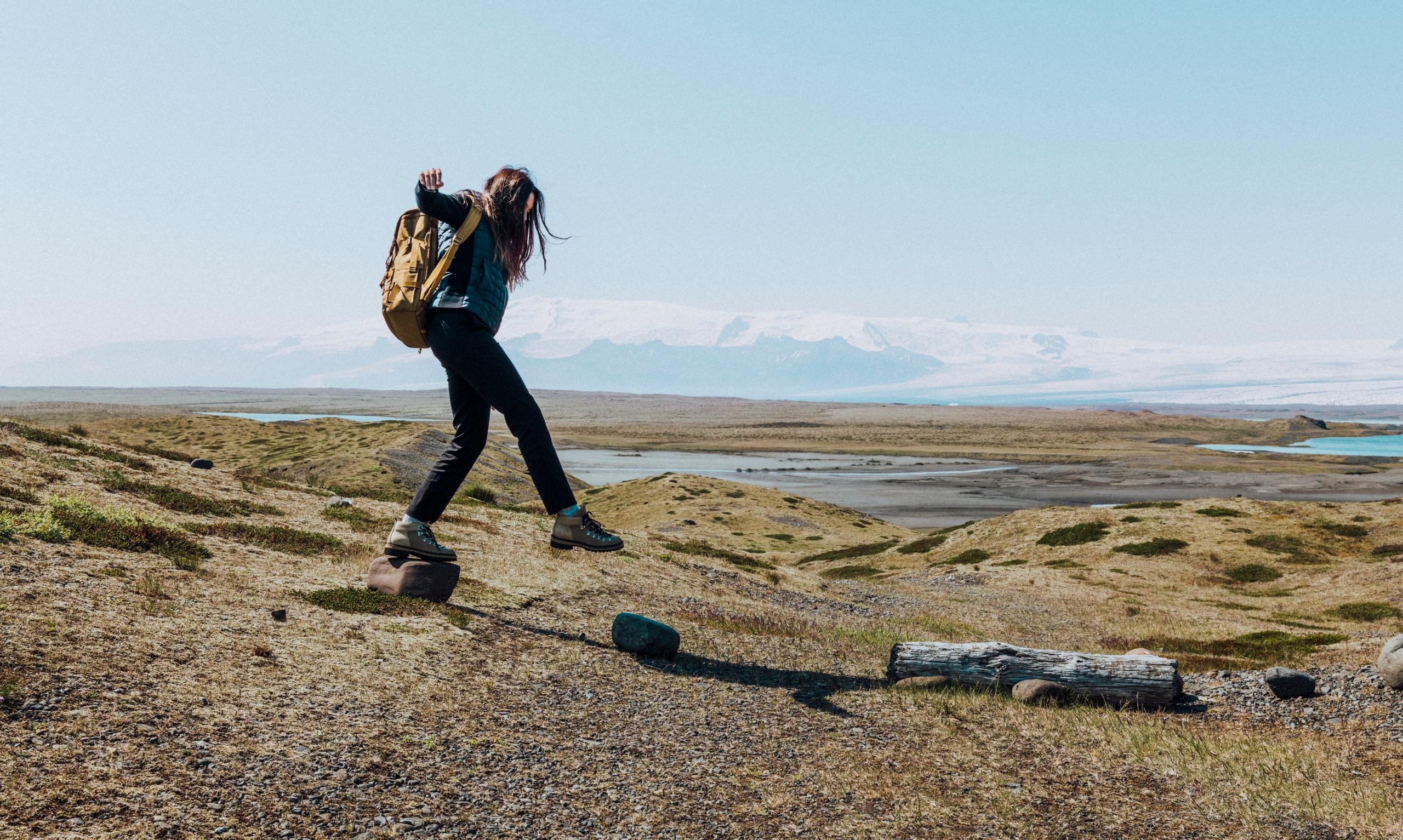 A woman in Phase Full-Zip walking on field in Iceland.