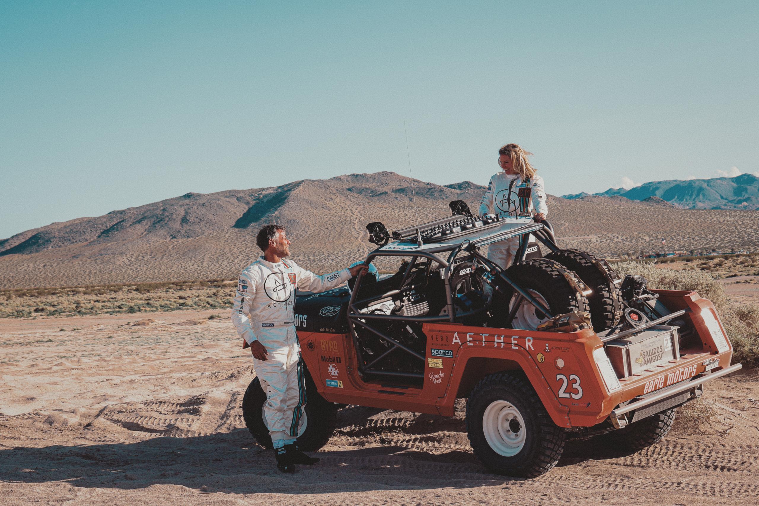 Man and woman standing next to customized 1969 Jeep Commando in a desert landscape