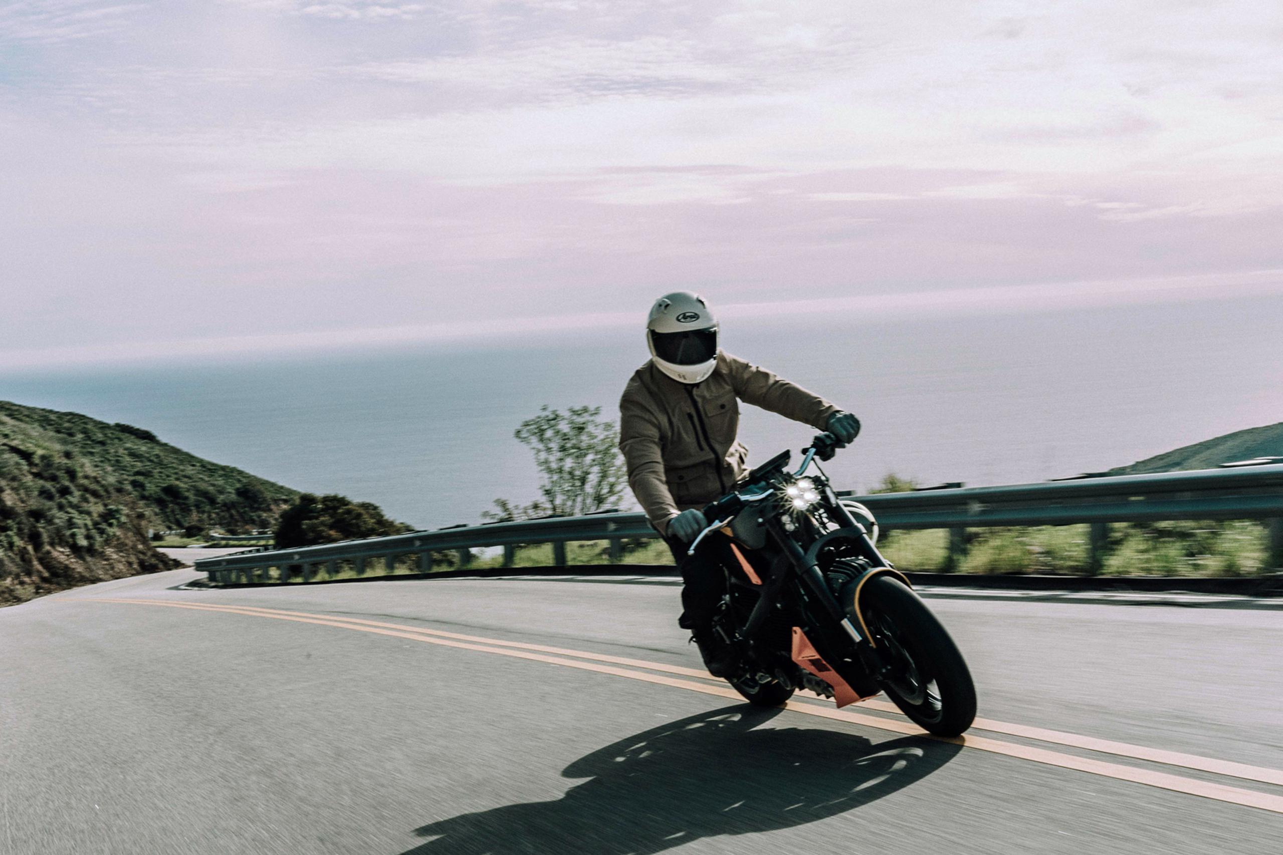 Man riding motorcycle on Pacific Coast Highway with ocean in the background