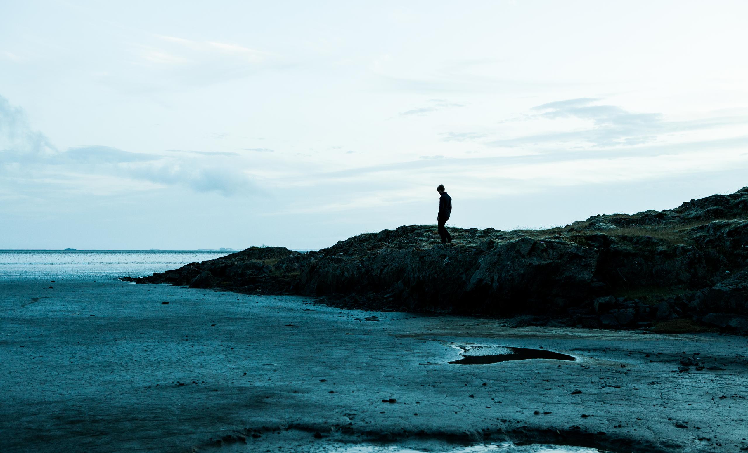Man walking alongside coastline in Iceland