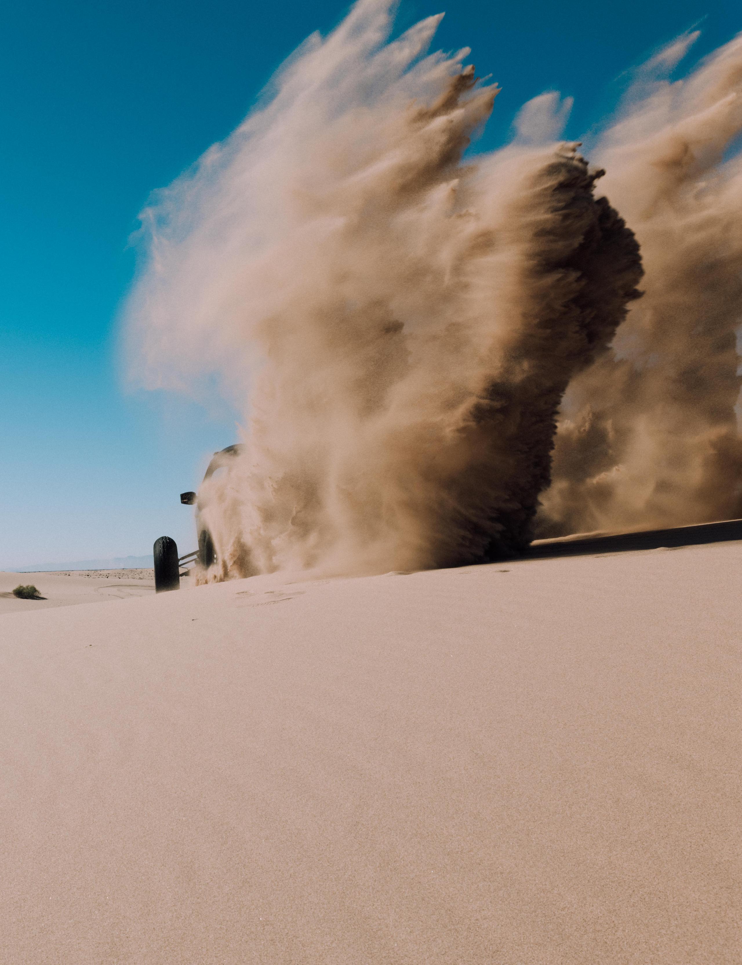 Quad speeding on Imperial Sand Dunes creating huge sand cloud behind