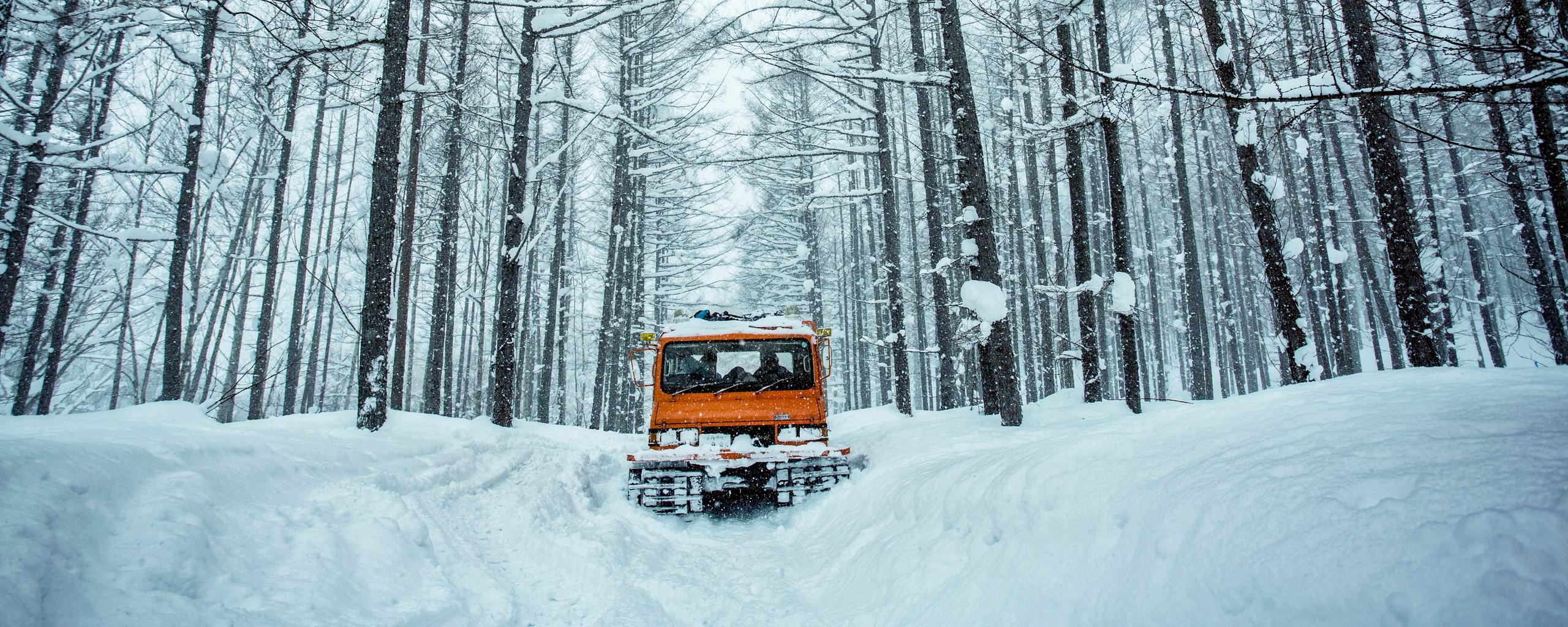 Orange snow truck against snowy white forest in Hokkaido Japan