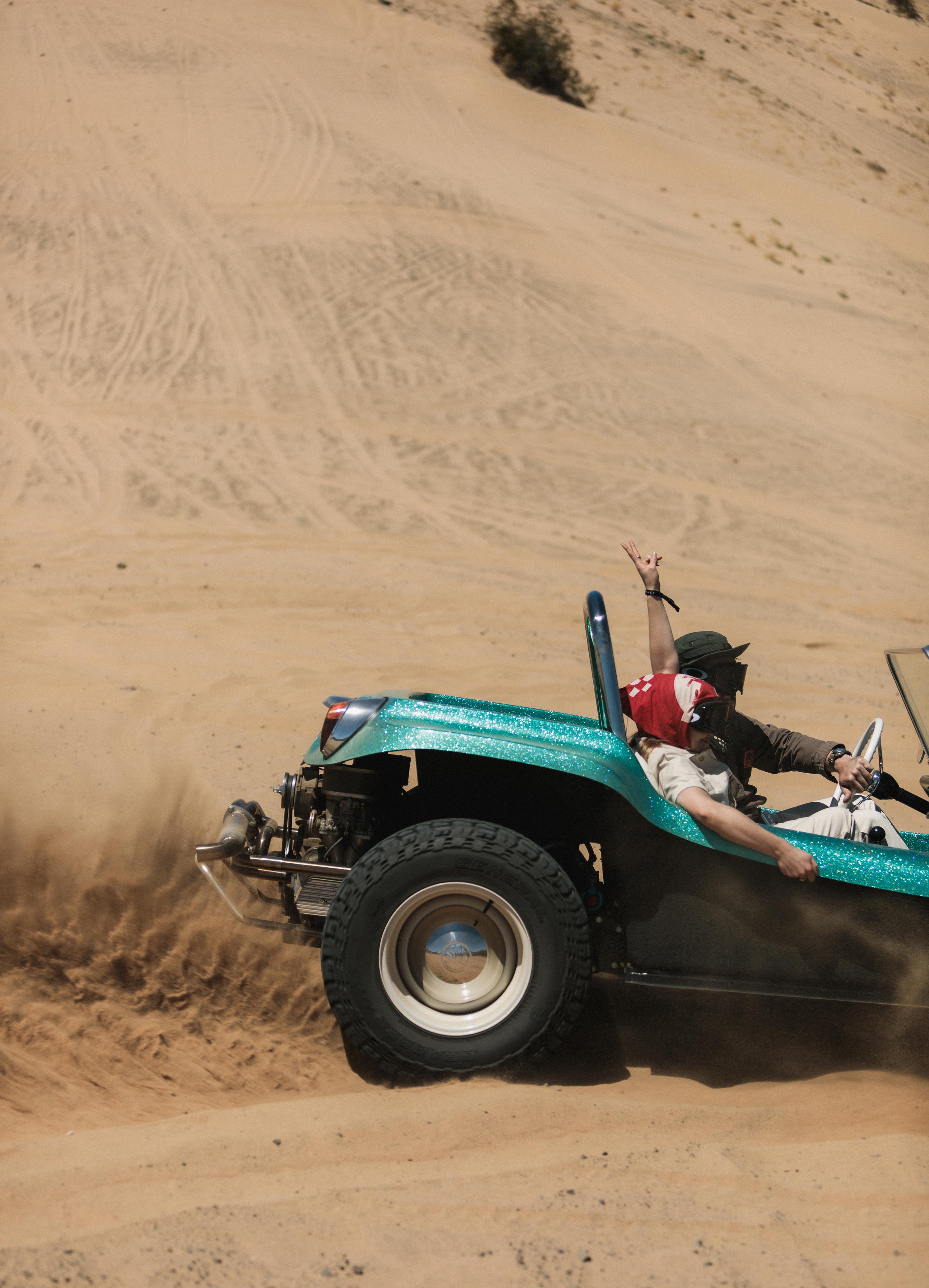 Man and woman in custom vehicle driving in Joshua Tree desert