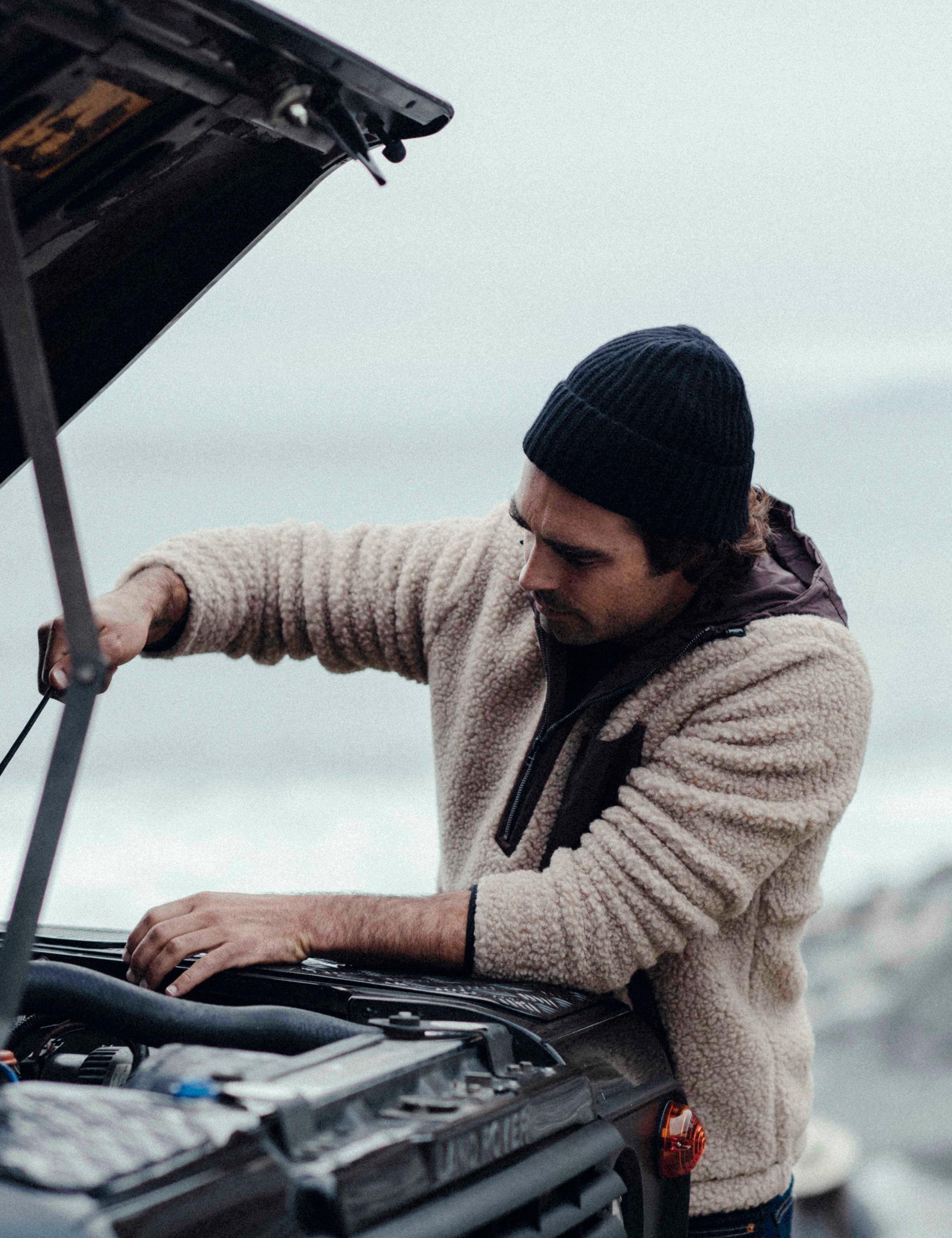 Men wearing Narrows Pullover repairing his car