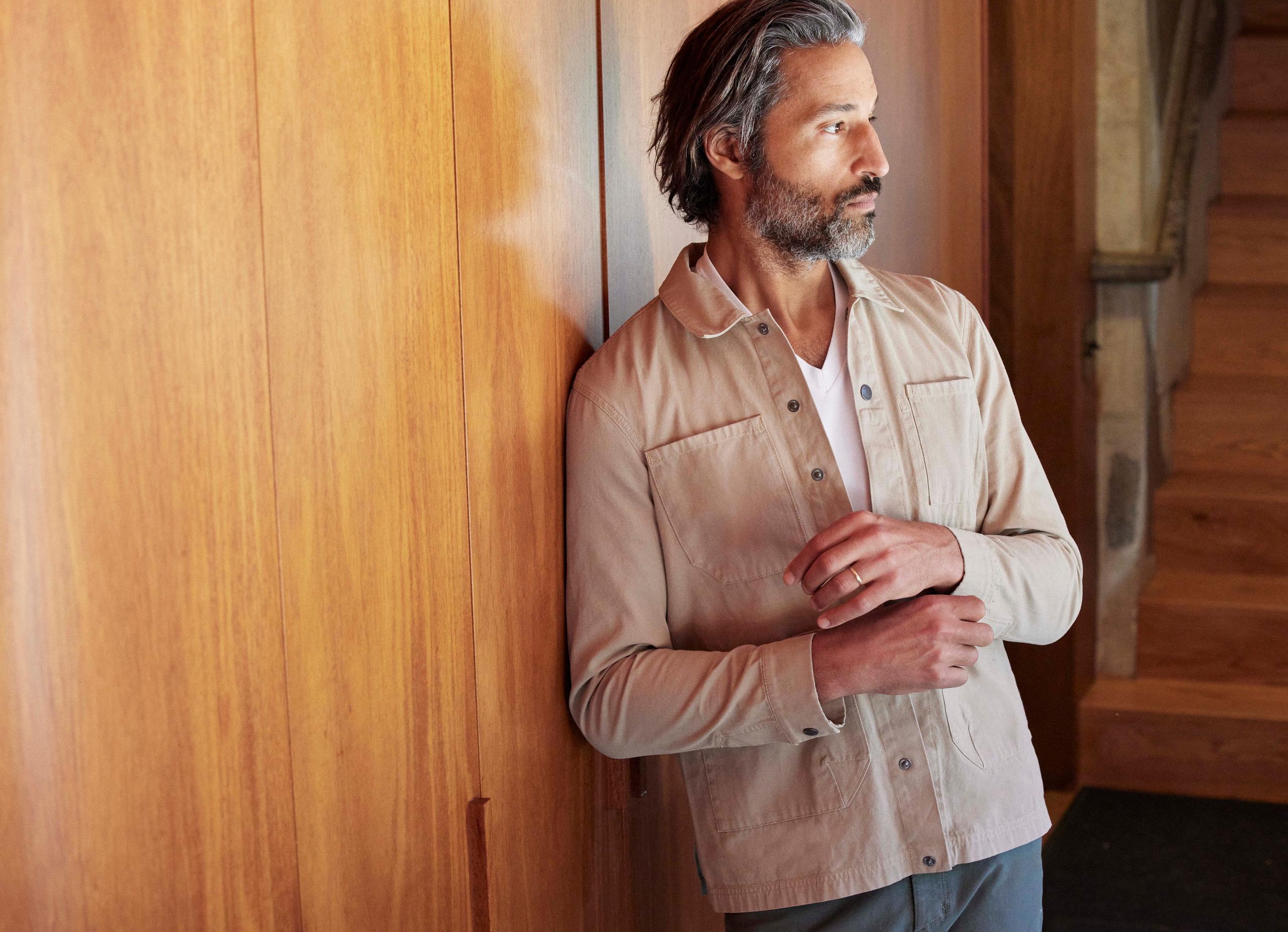 Man wearing Motto Cotton Chore Jacket leaning on wall of mid-century house interior