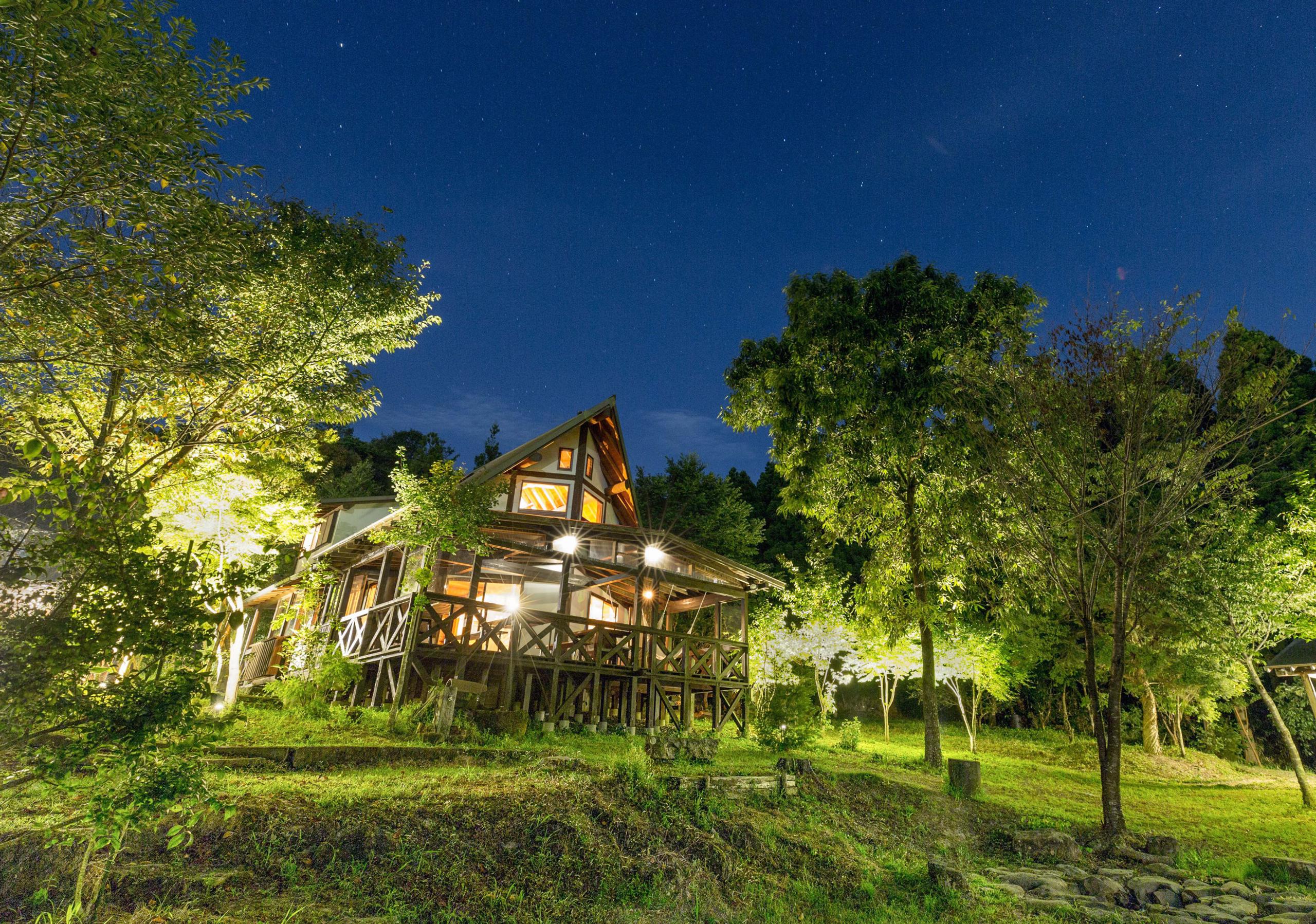 Night view of Yama Mountain house with forest lit up