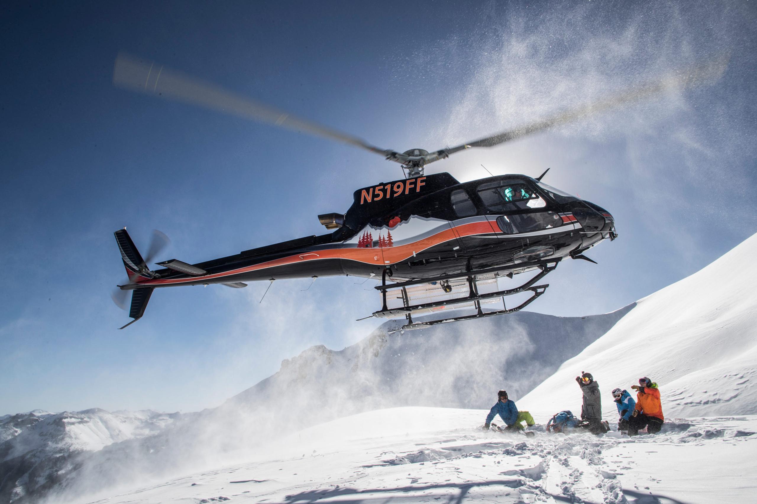 Helicopter dropping off skiers on mountain
