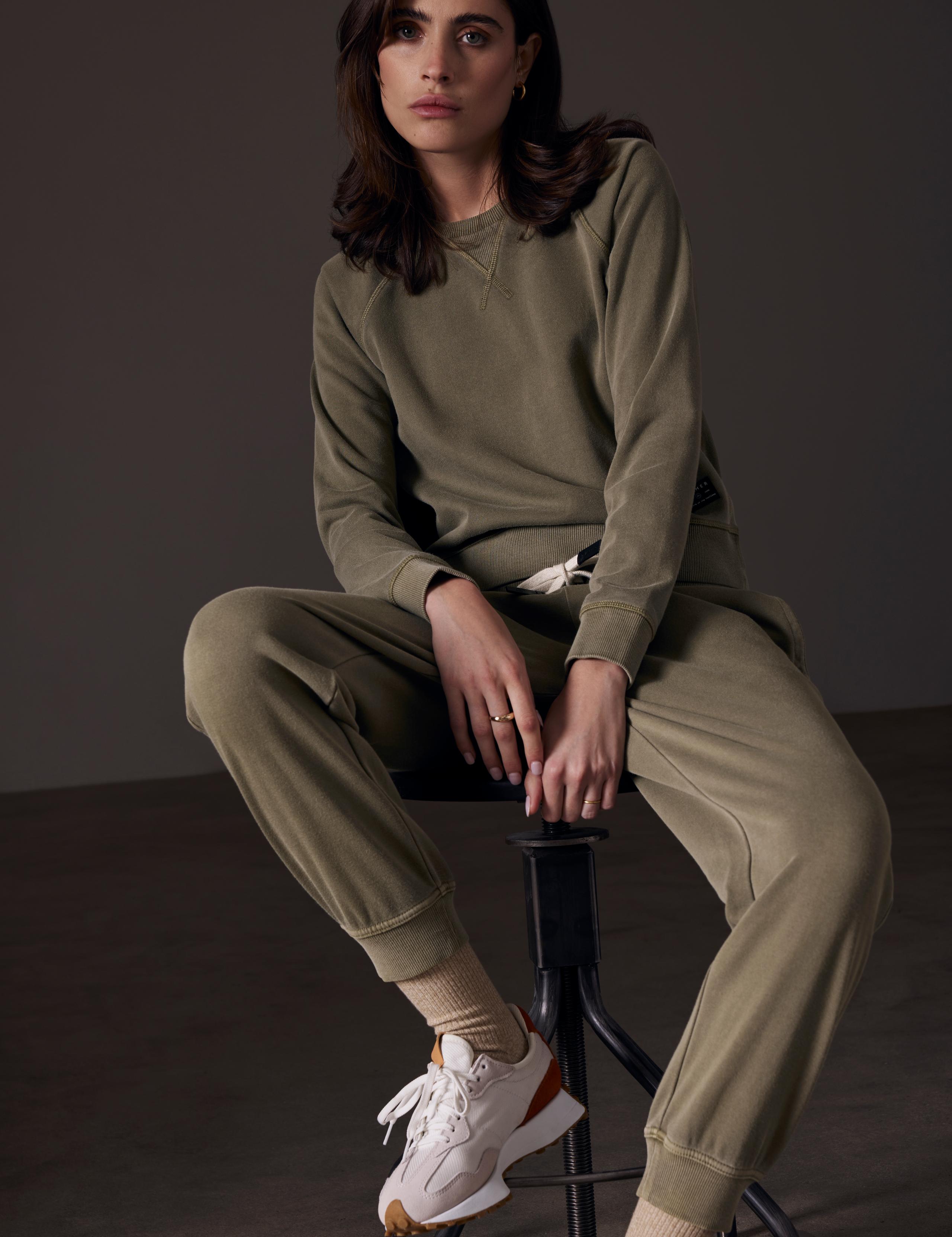 Woman sitting on stool in Solstice sweatshirt and jogger