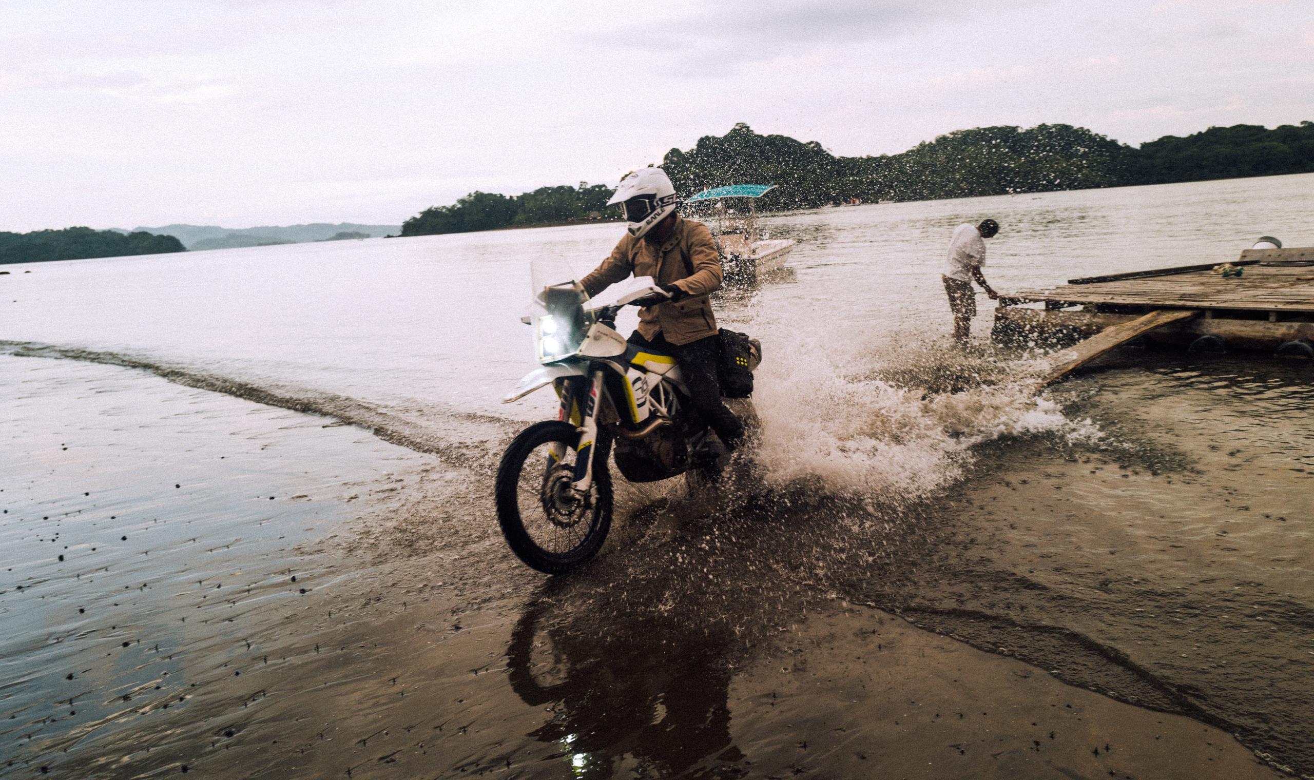 Motorcylist riding off dock onto coastline in Costa Rica