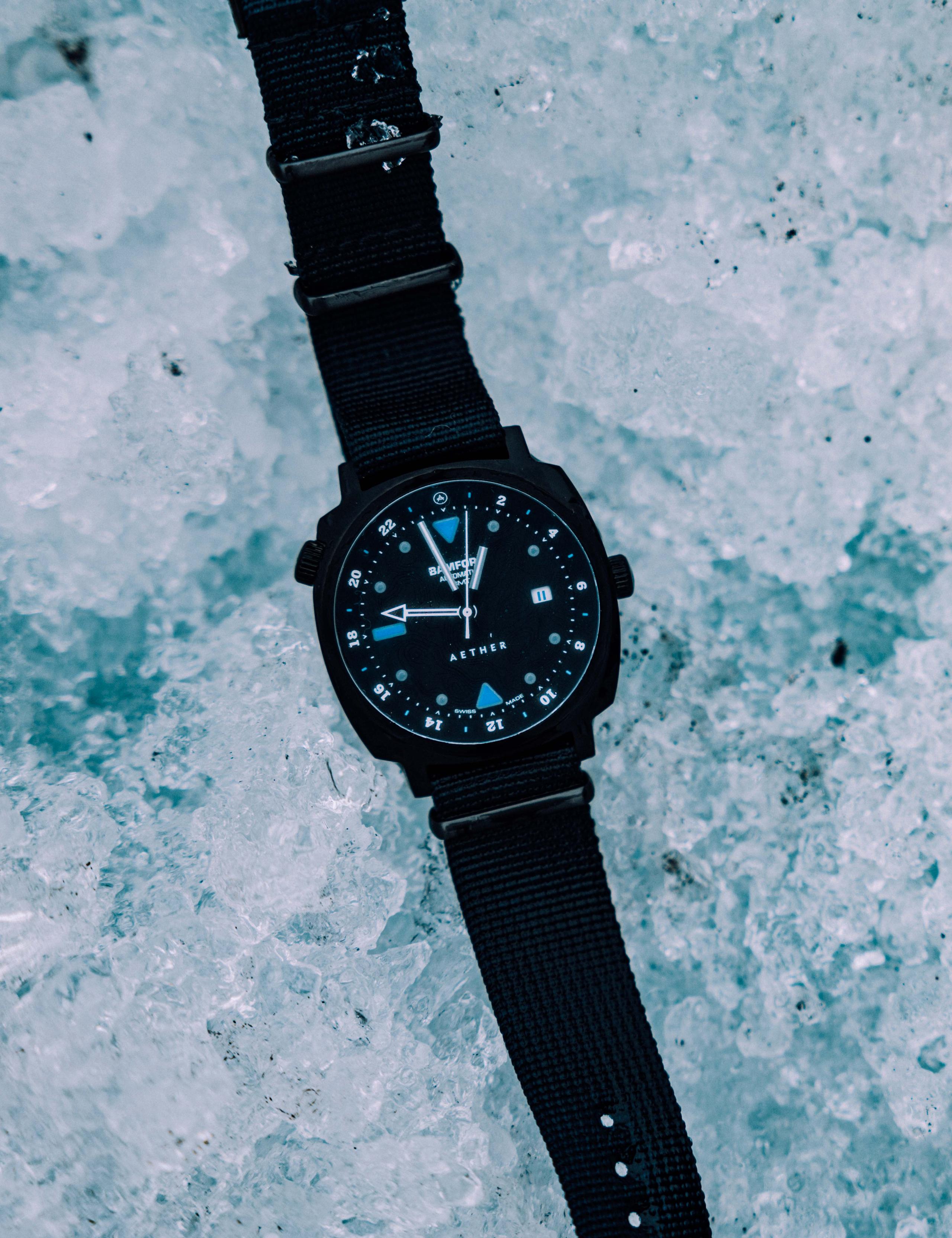 AETHER + Bamford GMT watch sitting on top of icy glacier
