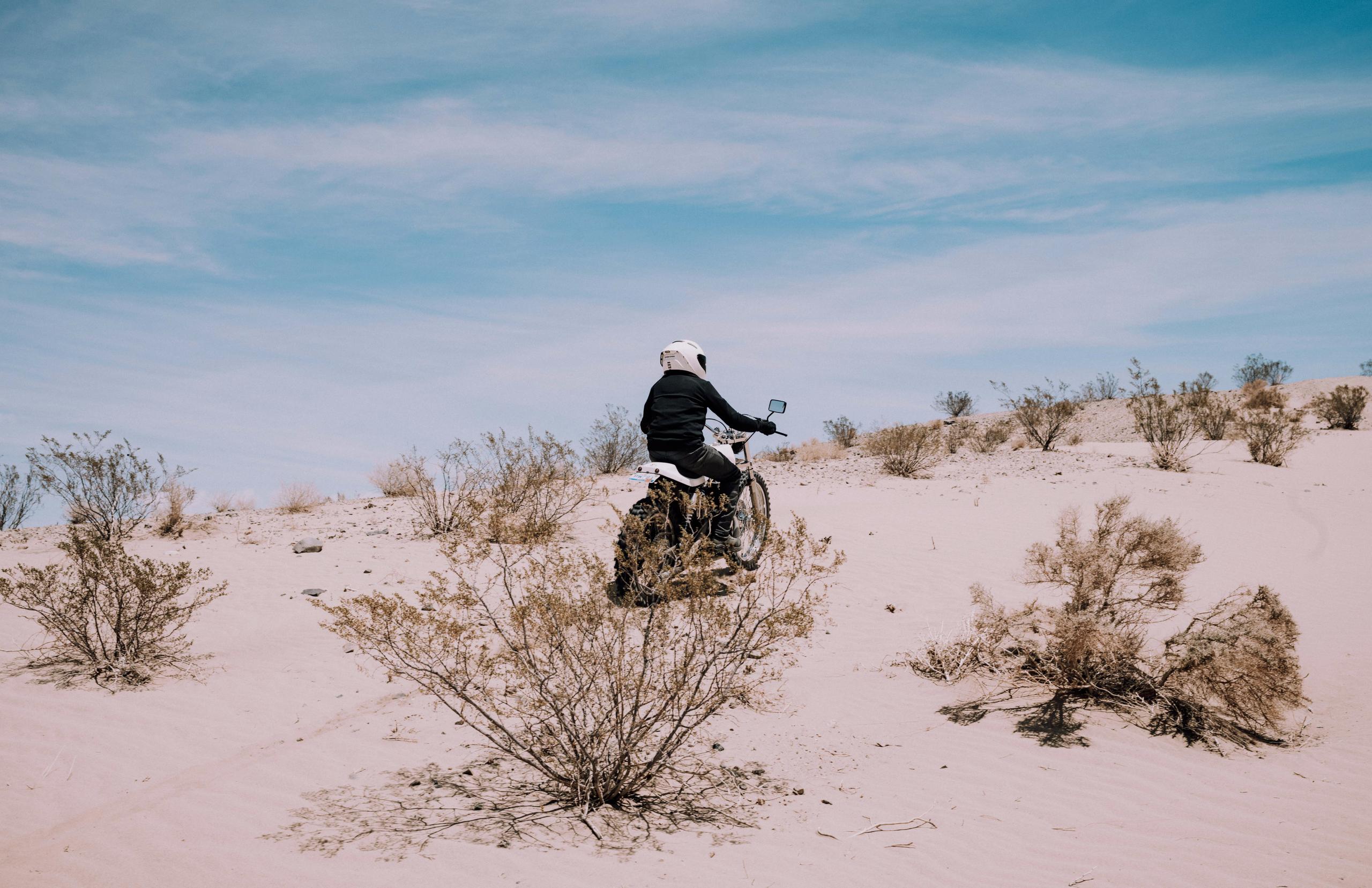 Man riding motorcycle through desert landscape