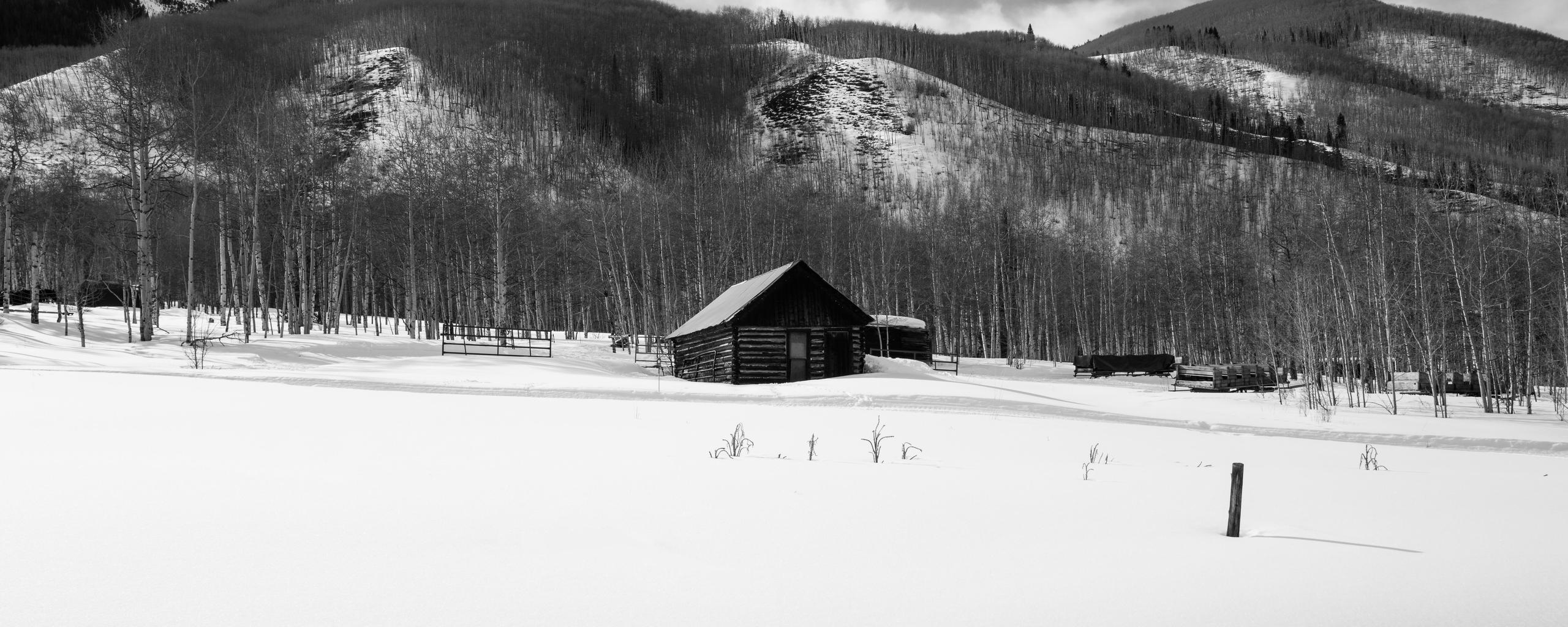 Black and white photo of cabin in front of snow mountains