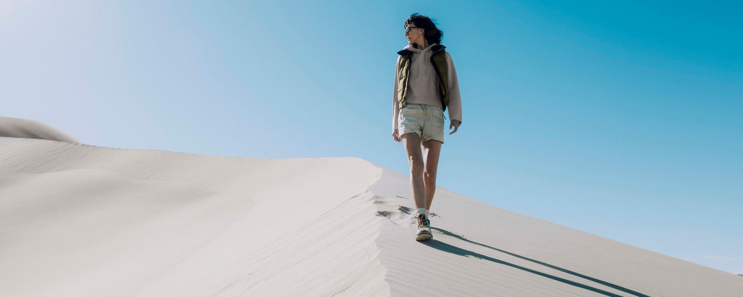 Woman walking down sand dune