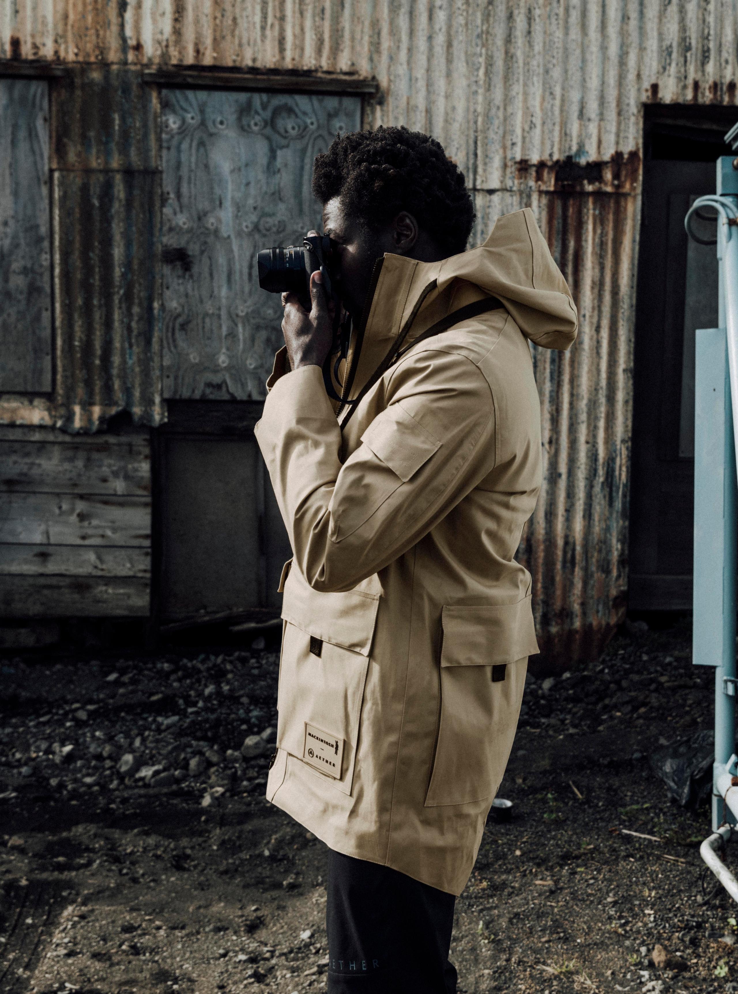 Profile of man wearing AETHER + Mackintosh Field Parka holding camera and taking a picture