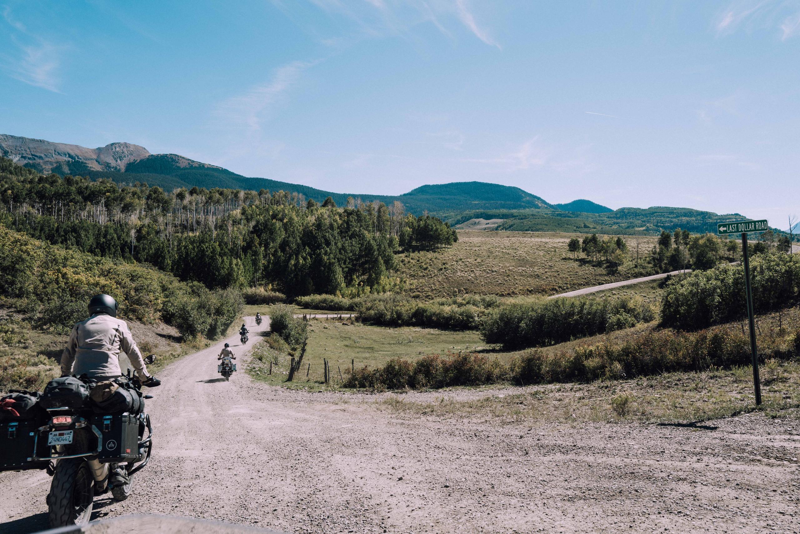 Motorcyclists riding on gravel road towards Rocky Mountains