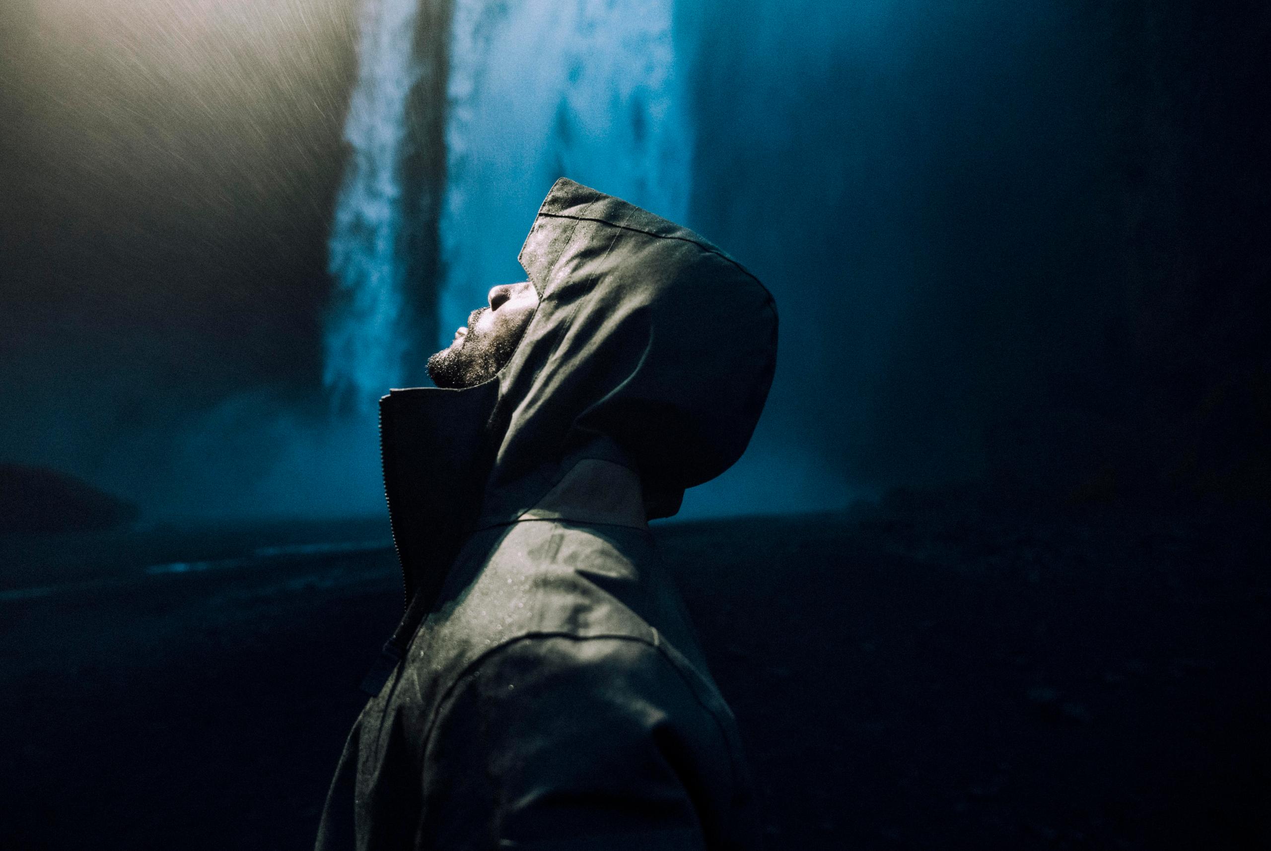 Profile of man wearing AETHER + Mackintosh Field Anorak next to waterfall in Iceland