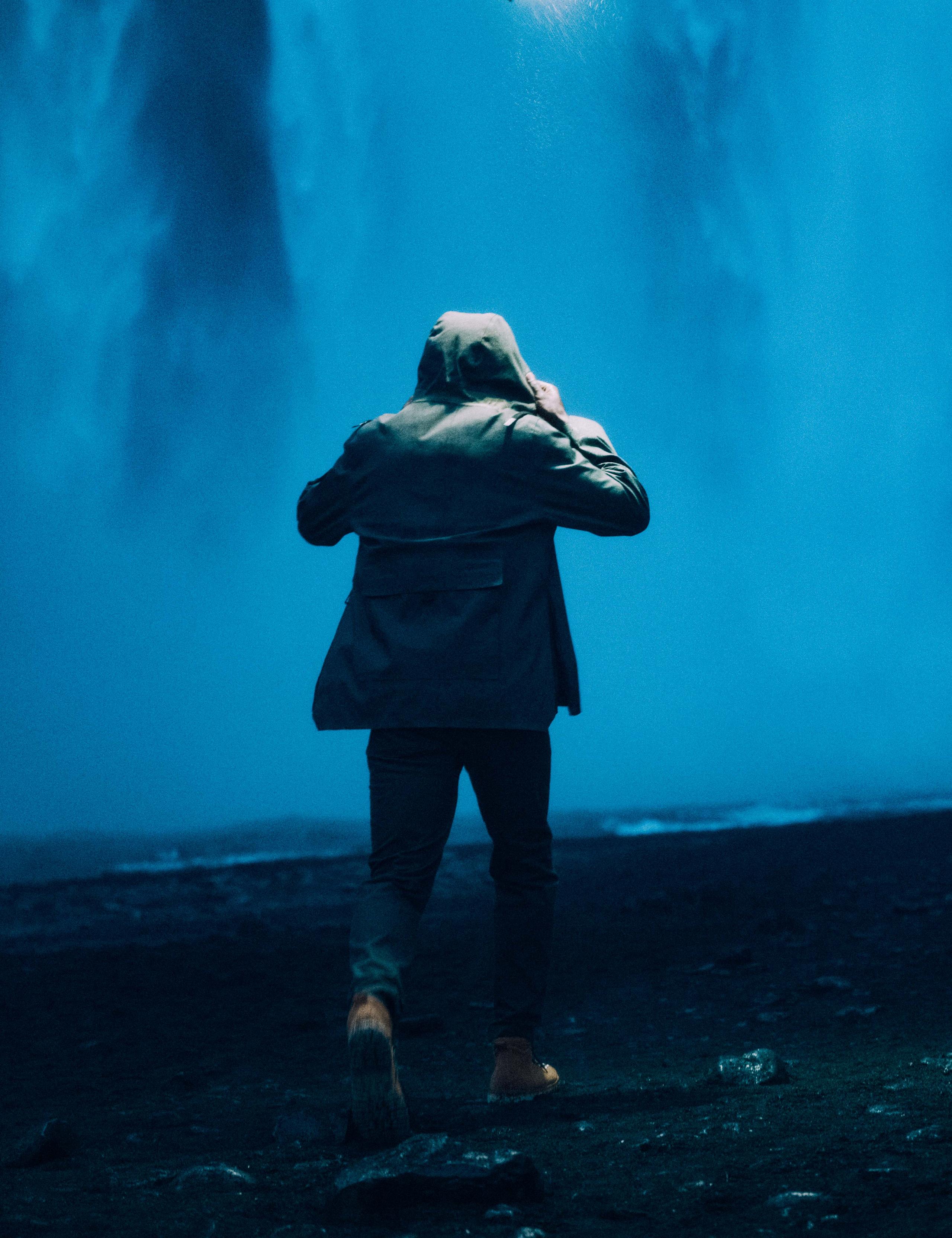 Man wearing AETHER + Mackintosh Field Anorak next waterfall in Iceland