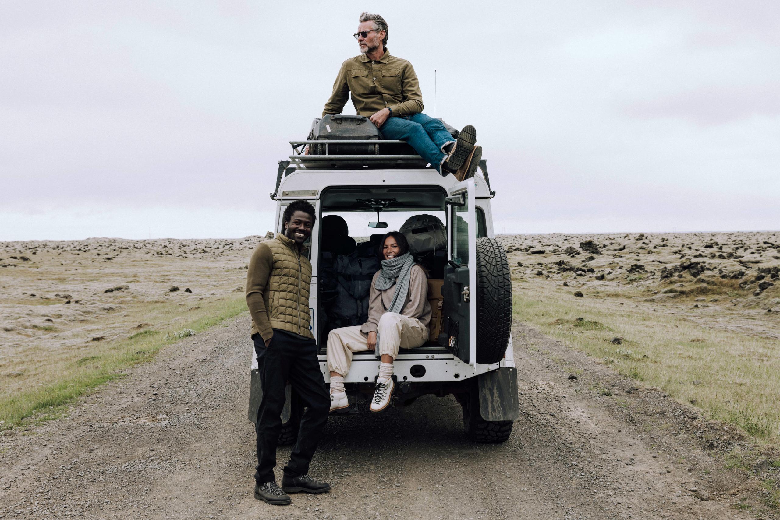 Group photo of two men and one woman on the back of a white Defender in Iceland landscape