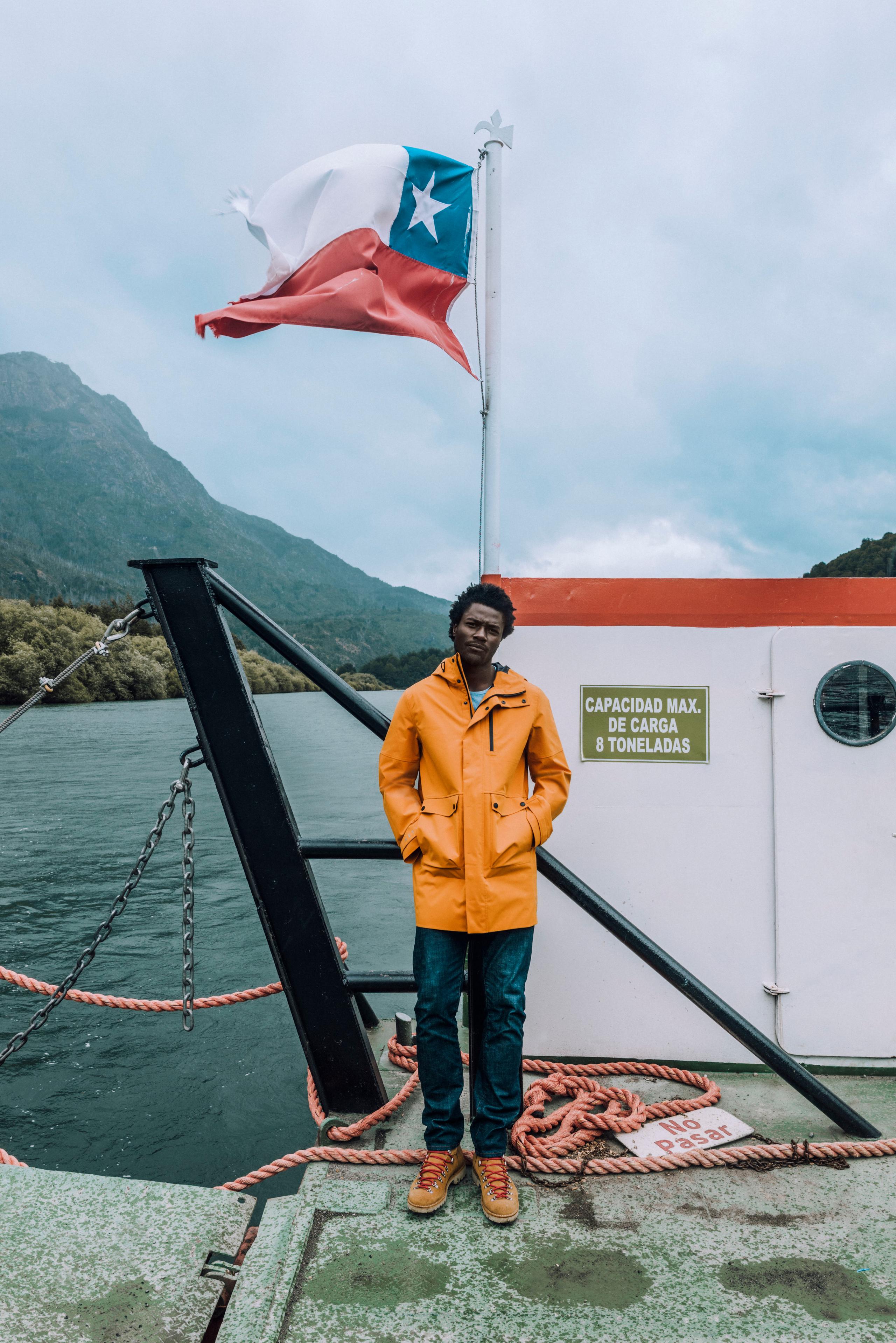 Man in orange jacket standing on a boat.