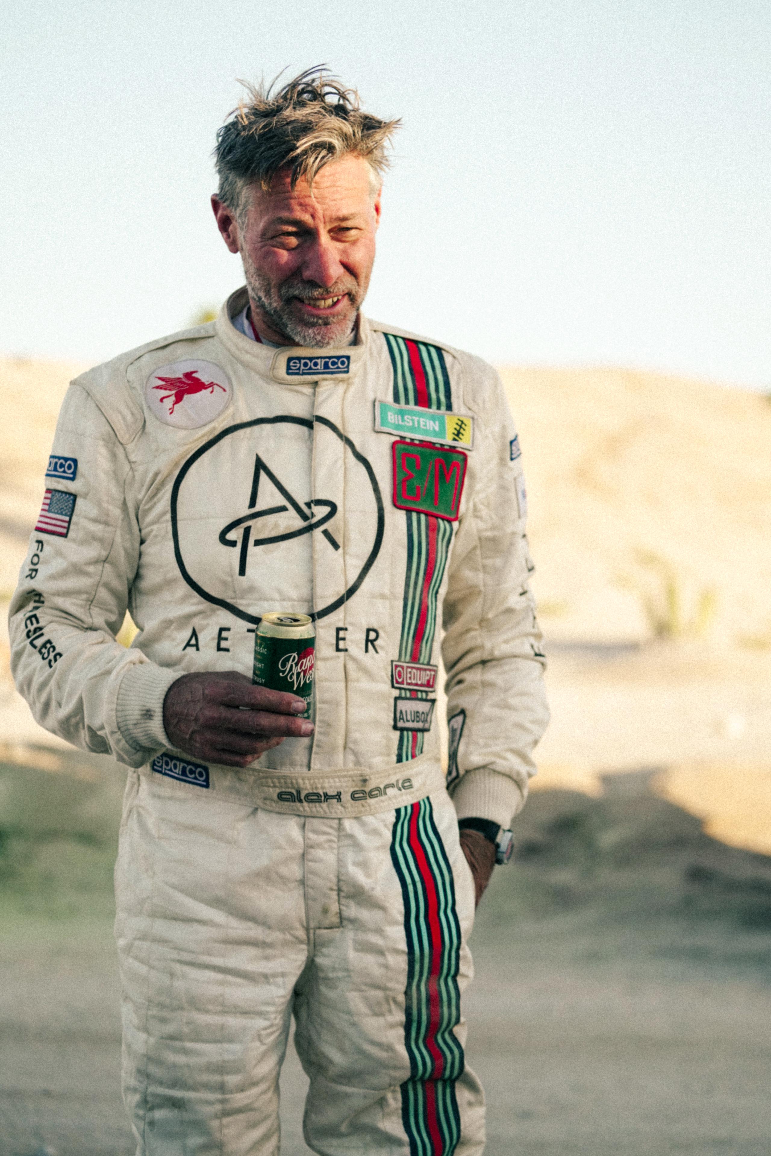 Alex Earle in racing uniform standing in desert