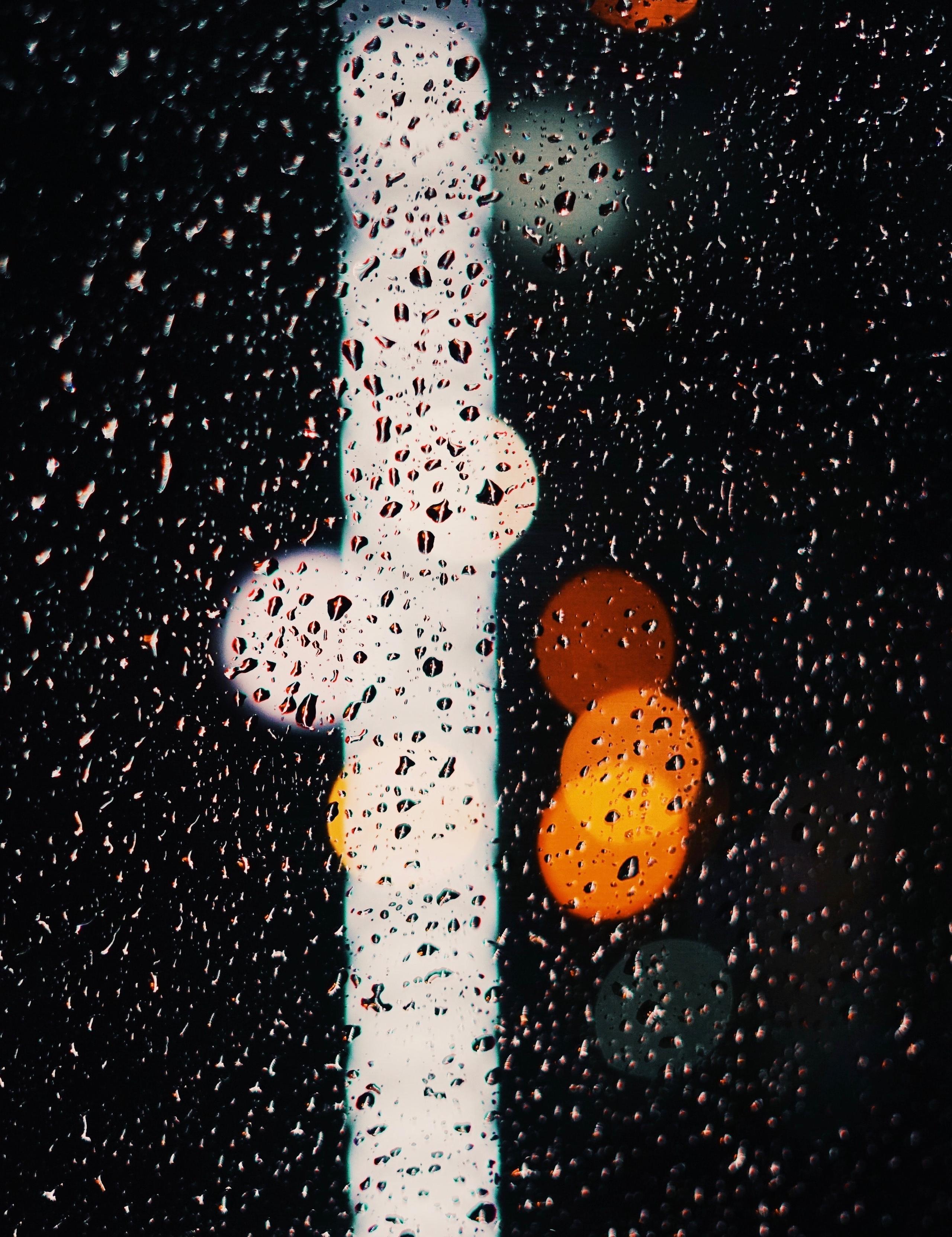 Detail of rainy window at night with blurry lights