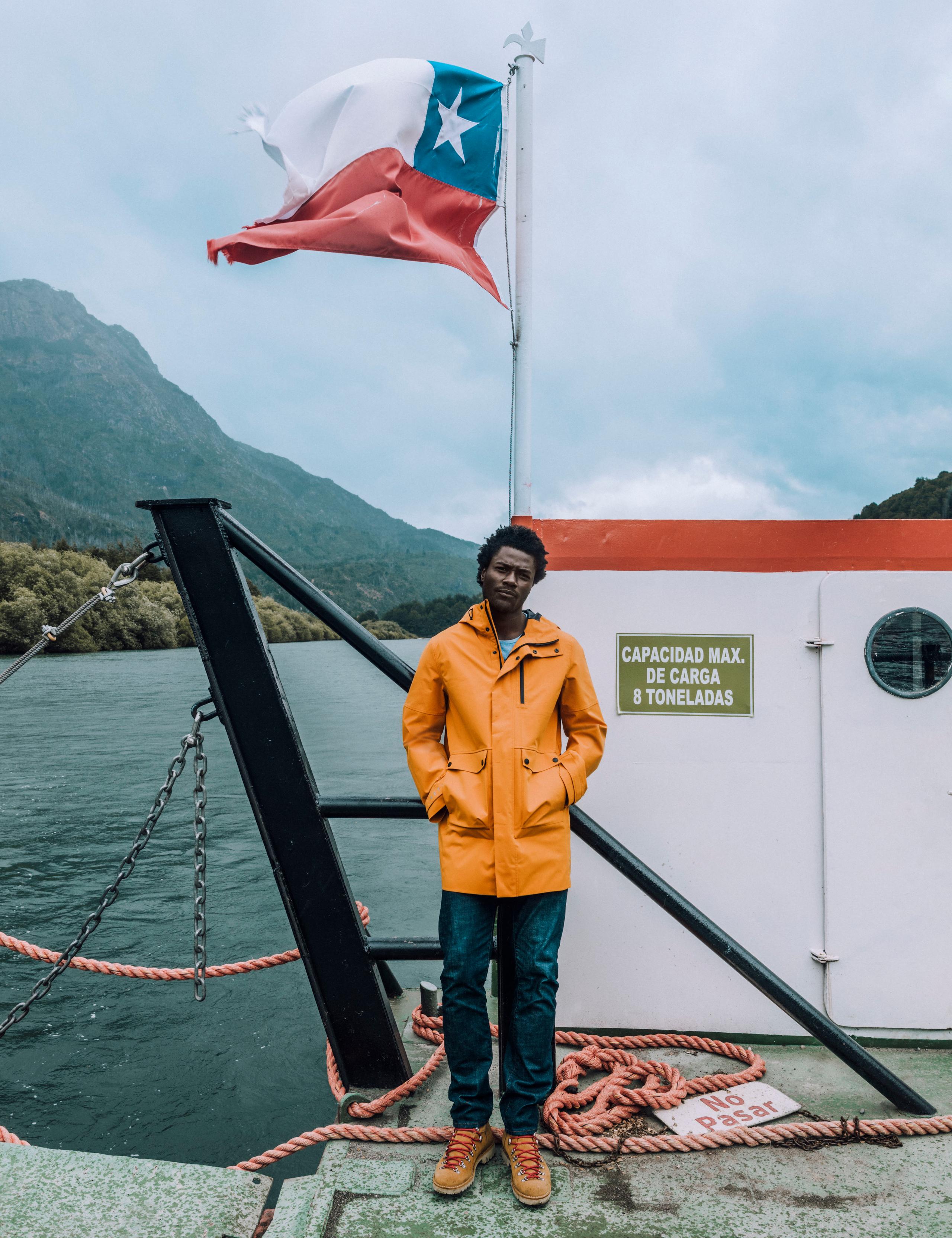 Man in Anders Rain Jacket standing outside next to Chilean state flag in the Patagonia region