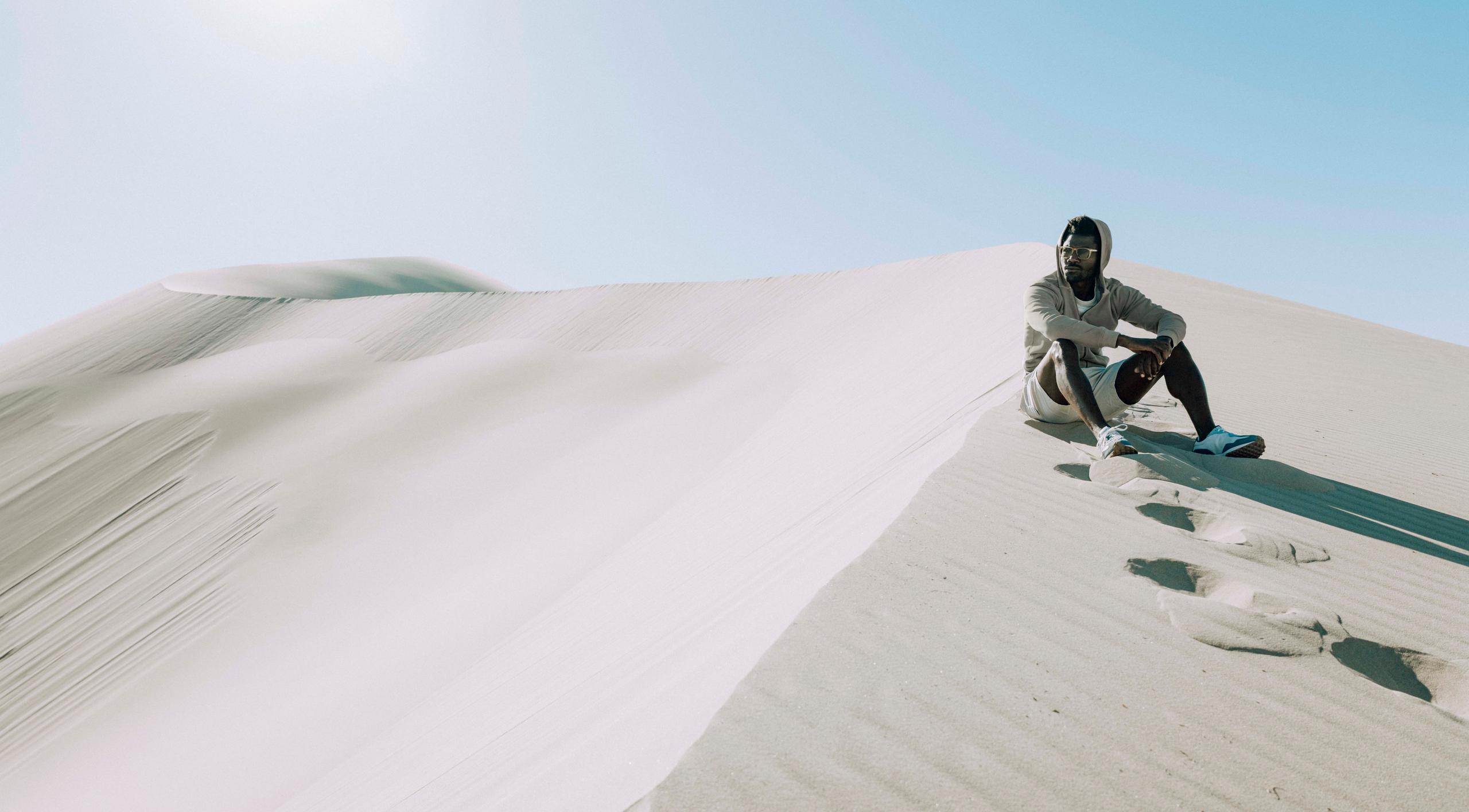 Man in Solstice Lightweight Full-Zip Hoodie sitting on desert.