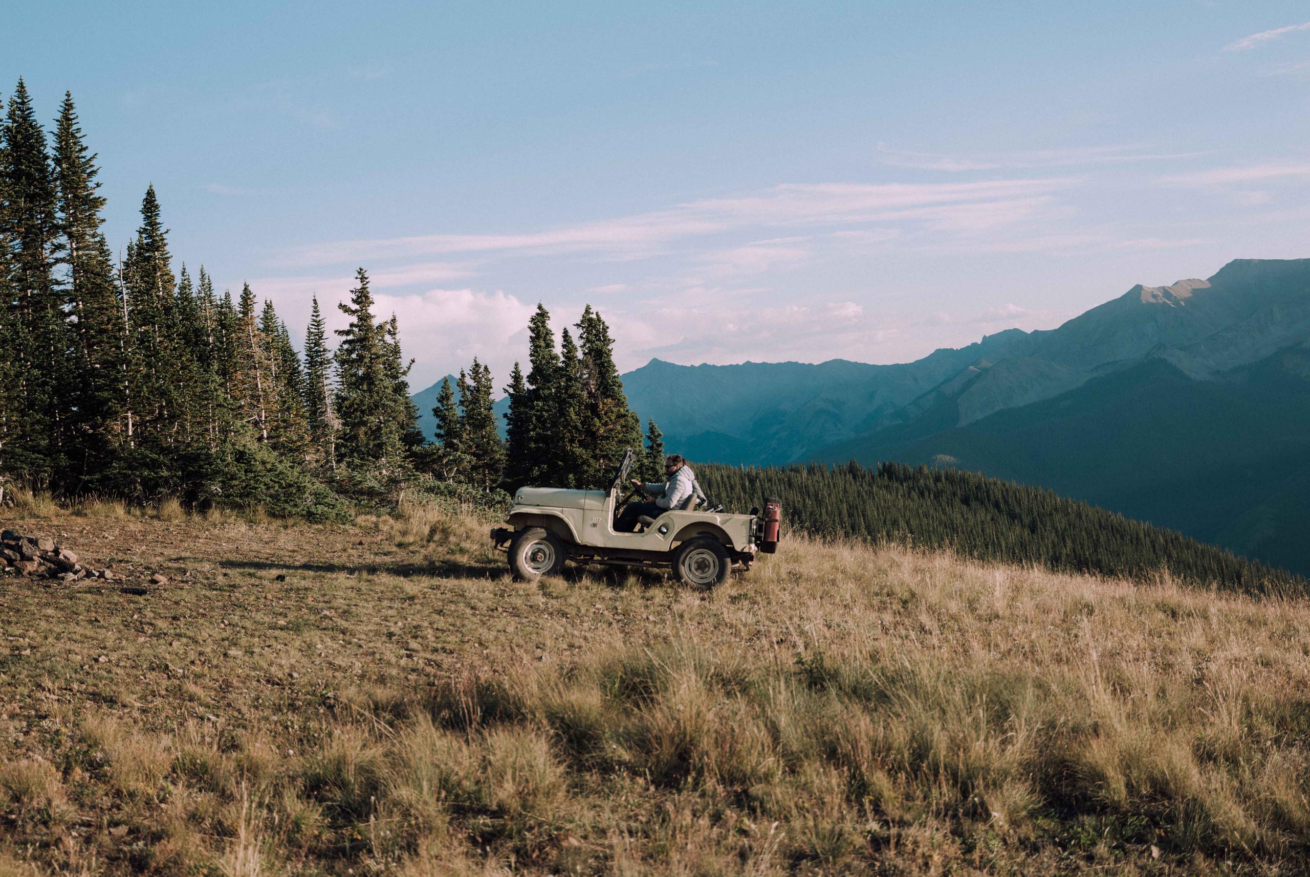 Mountain landscape with man in vintage Jeep