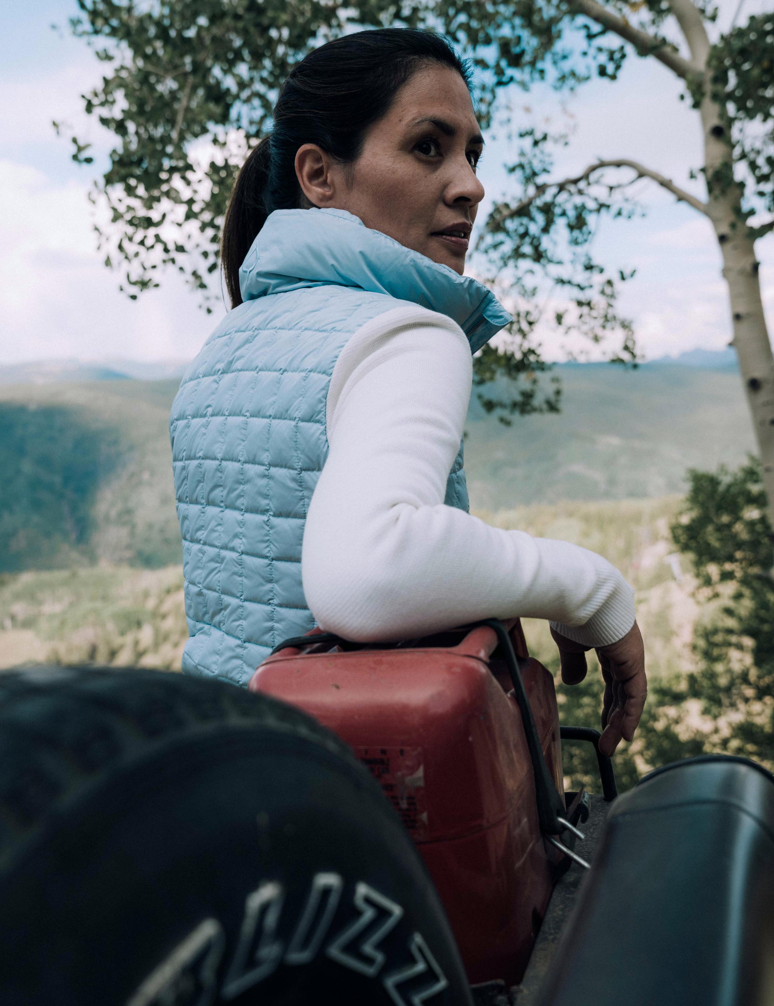 Woman with arm leaning on gas can in back of vintage Jeep