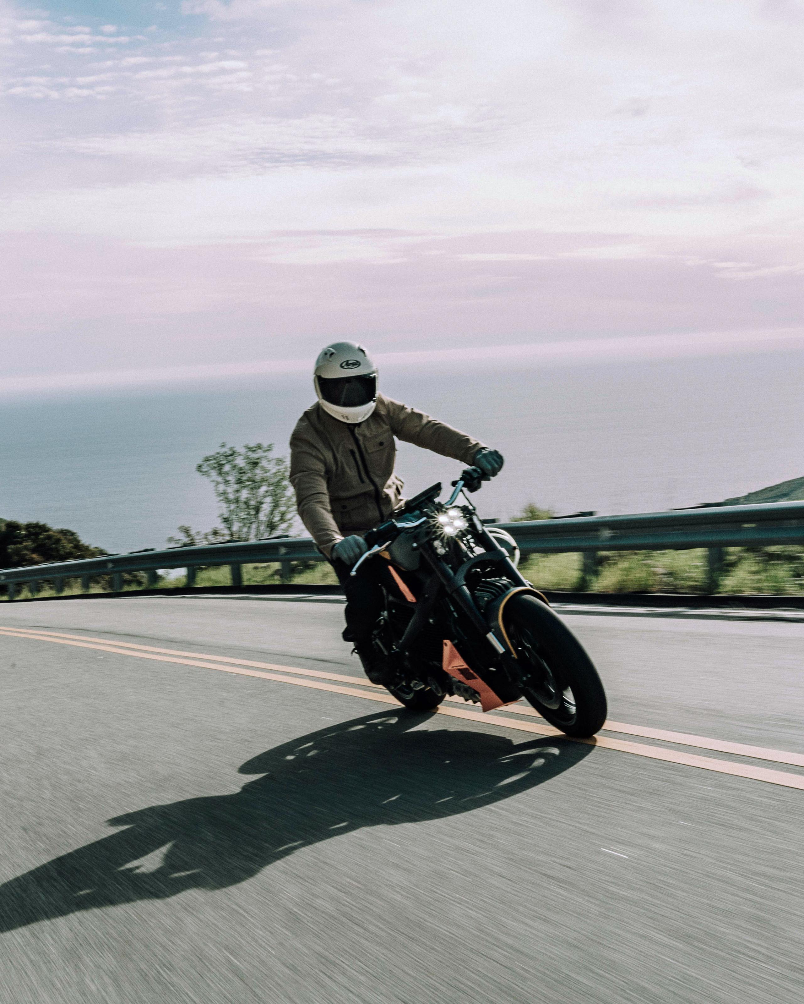 Motorcyclist in Mulholland riding up Malibu hills with Pacific Ocean in the background