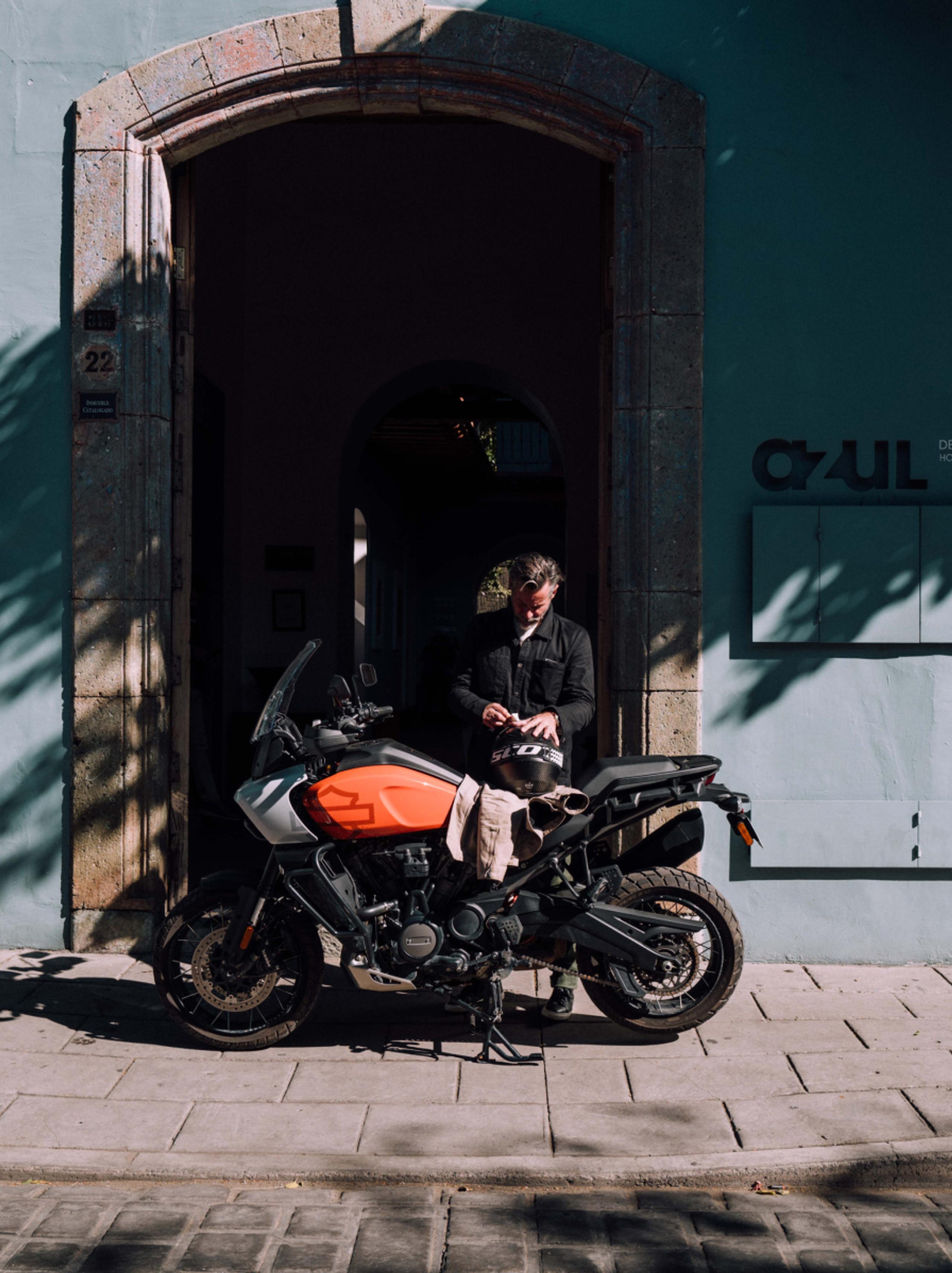 Man standing next to motorcycle in front of building in Oaxaca