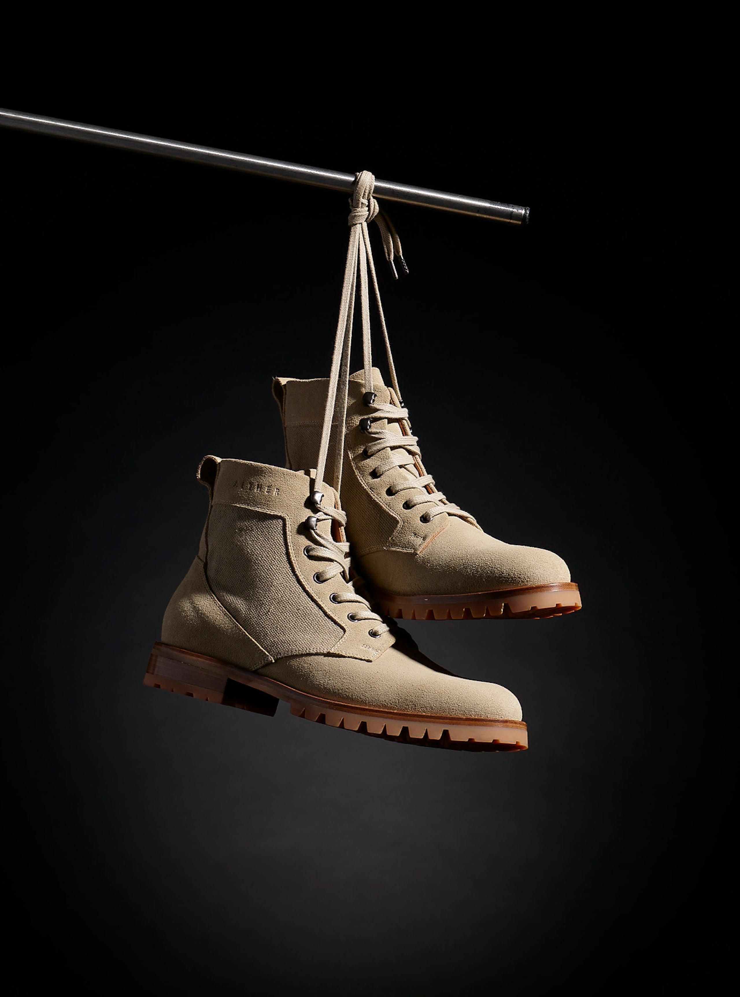 Ojai Boots hanging from laces in studio against black background