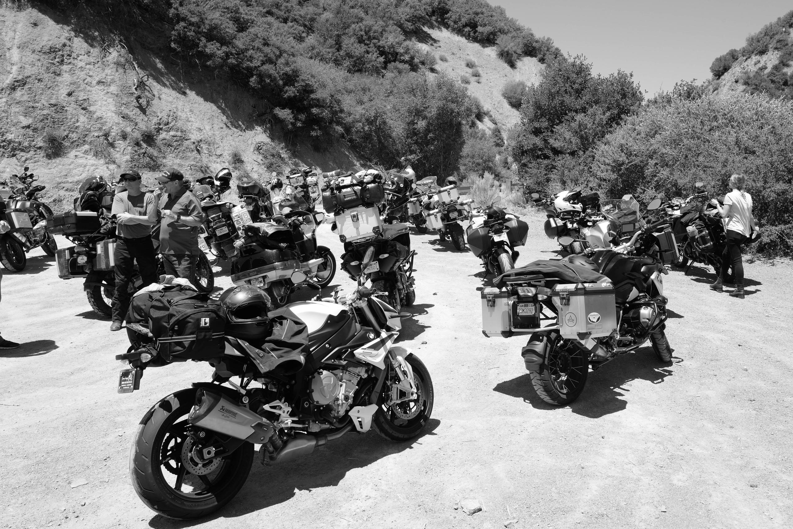 Black and white photo of group of motorcycles parked on gravel turnout in Central California road