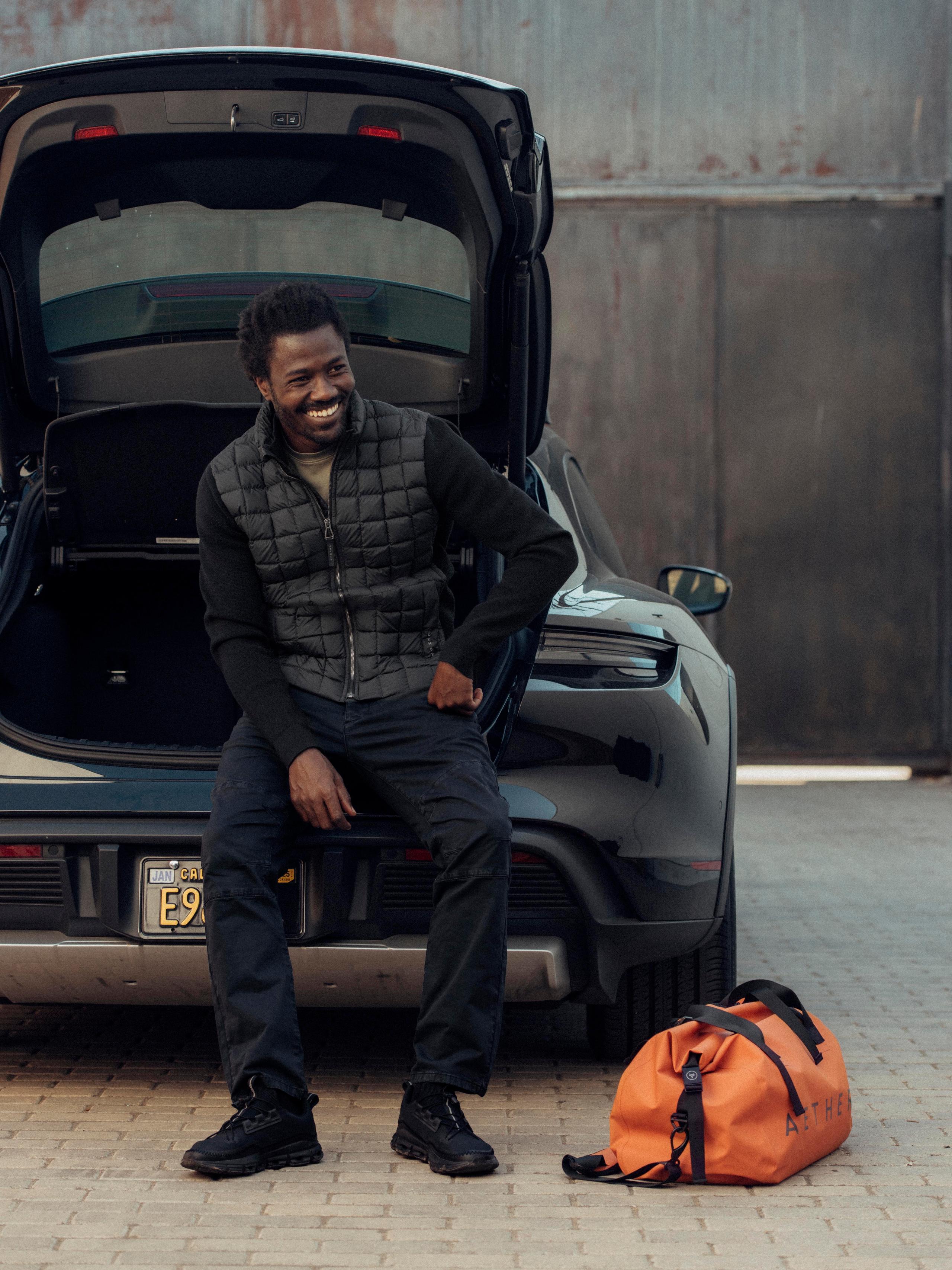 Juxtaposed photos of man sitting on back of Porsche with AETHER duffle bag next to the same man holding the duffle on mountainside in New Zealand