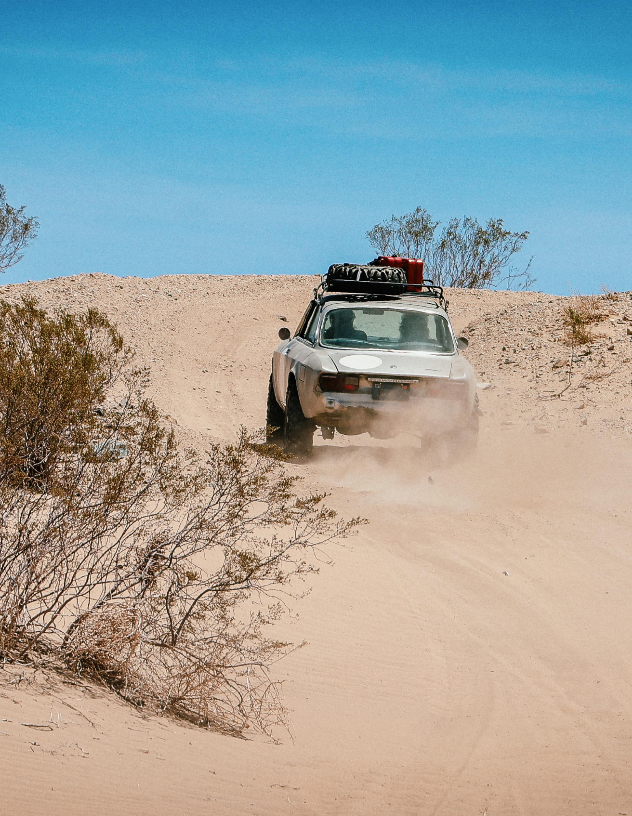 Vintage car driving through the Joshua Tree desert landscape