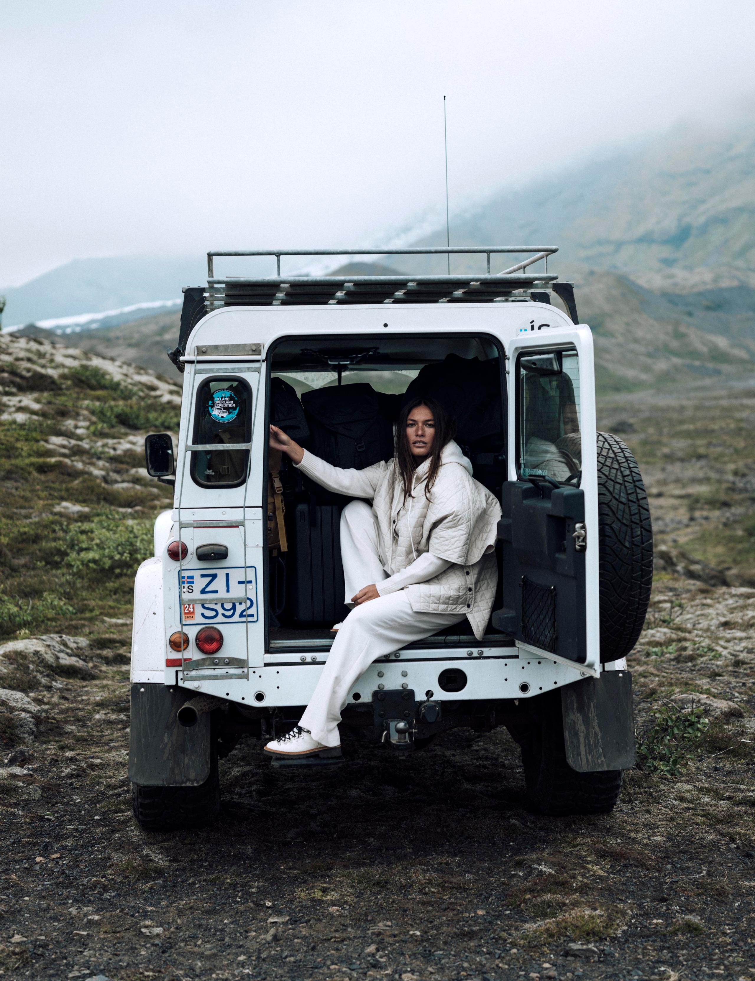 Woman lounging in back of white Defender in Iceland landscape